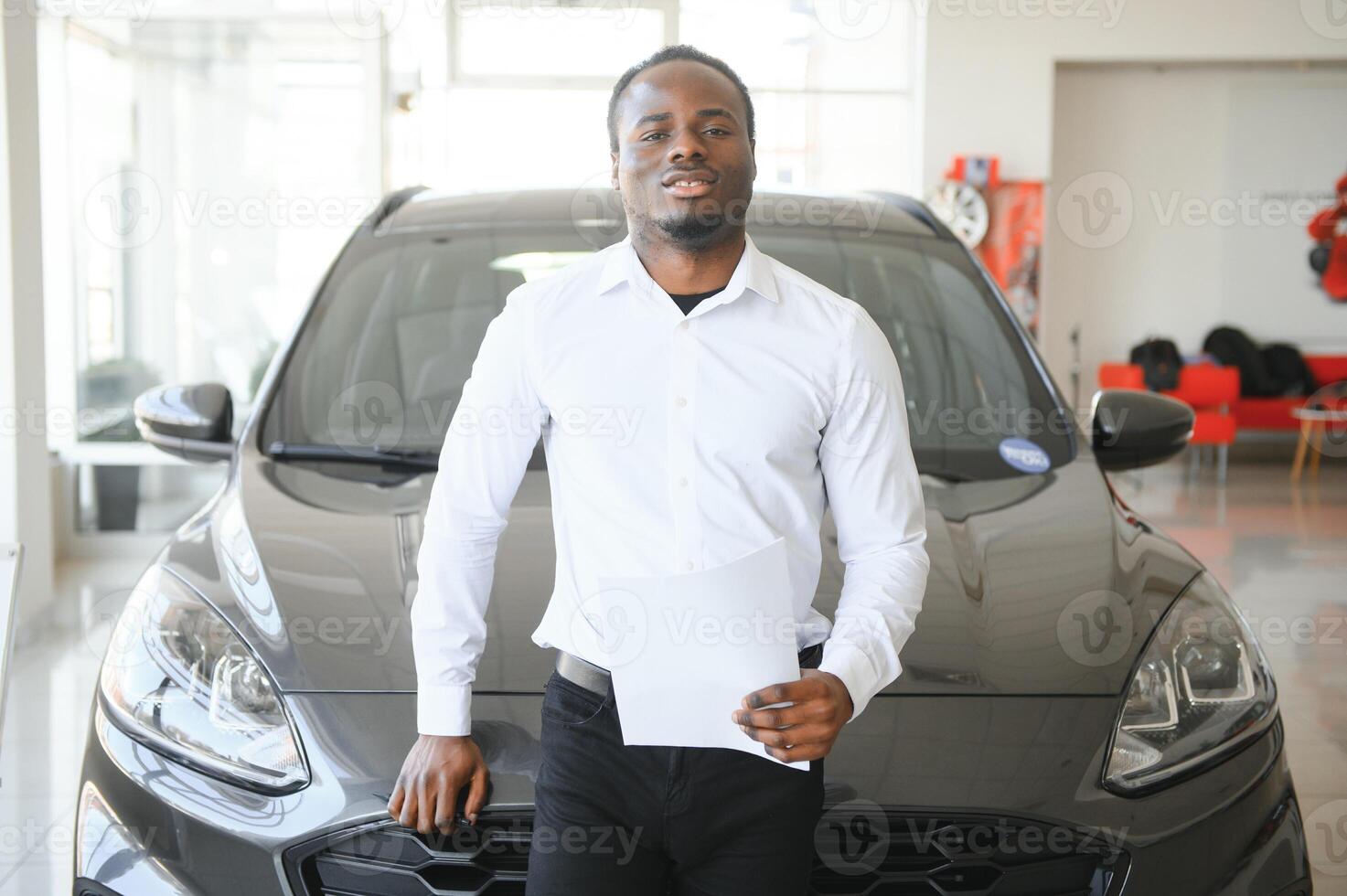 portret van knap Afrikaanse Amerikaans verkoper Bij werkplaats in auto toonzaal foto