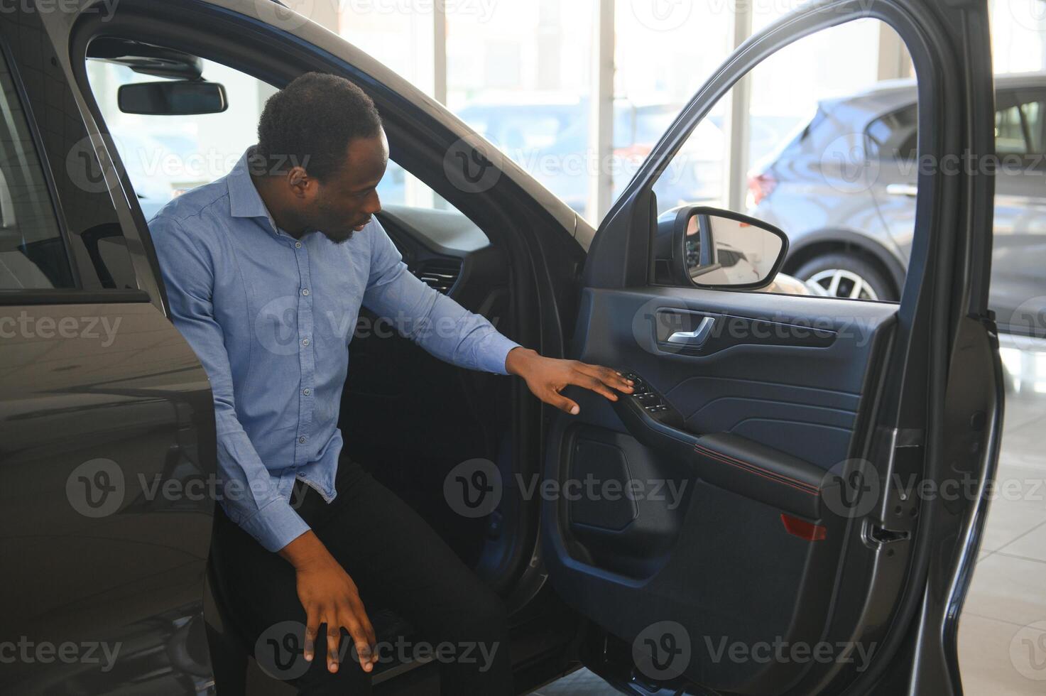 auto baasje. blij afro vent lachend, zittend in nieuw auto- het rijden van handel winkel foto