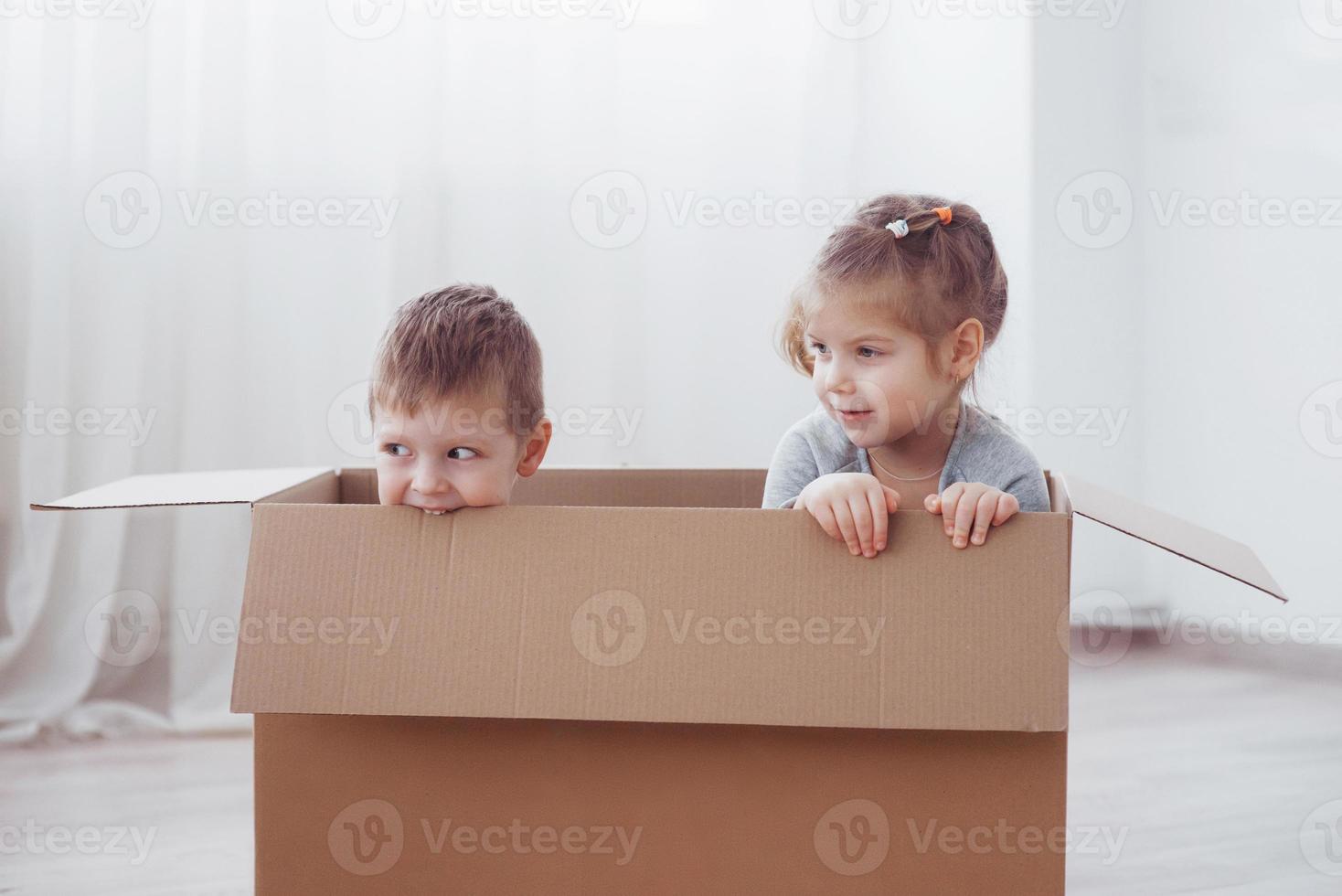 twee kleine kinderen jongen en meisje spelen in kartonnen dozen. concept foto. kinderen hebben plezier foto