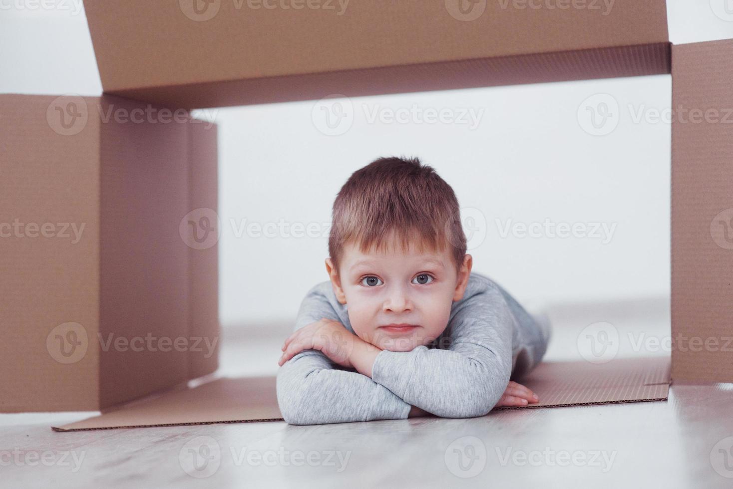 kind peuter jongen spelen in papieren doos. jeugd, reparaties en nieuw huisconcept foto