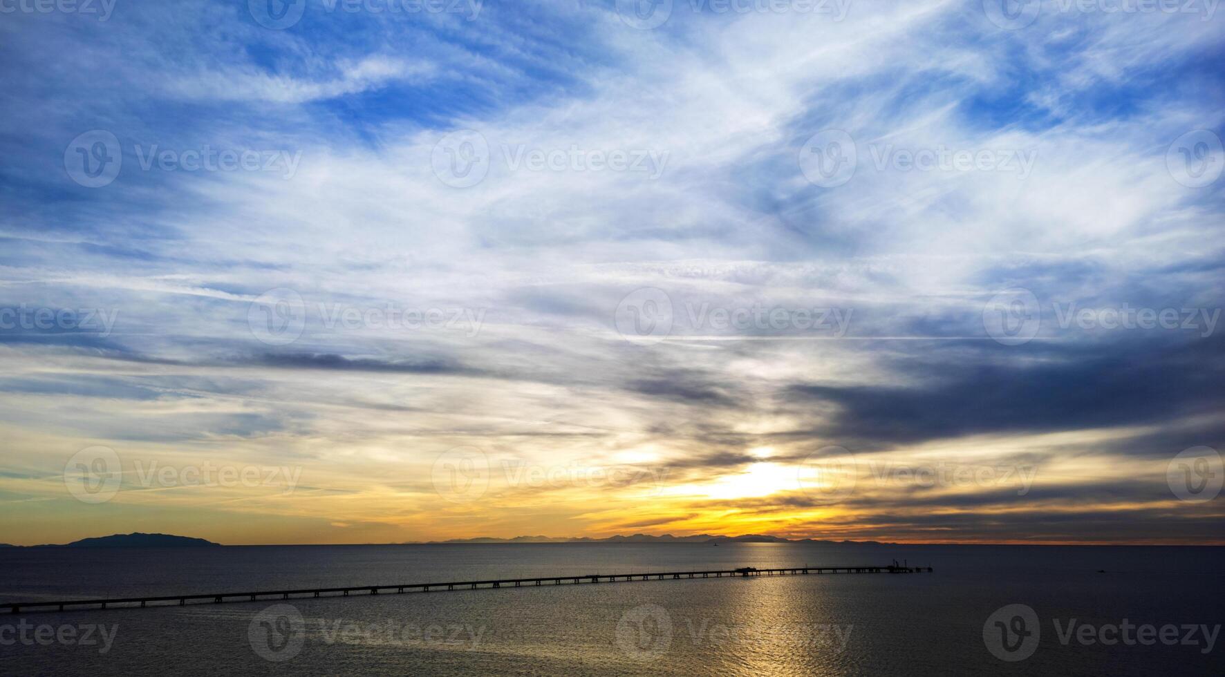 een spectaculair zonsondergang met pier en eilanden in silhouet foto