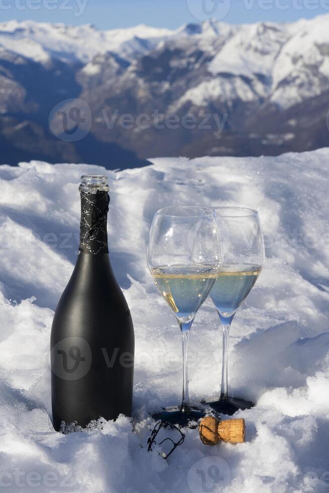 een fles van Champagne en twee bril zittend Aan een sneeuw gedekt oppervlakte foto