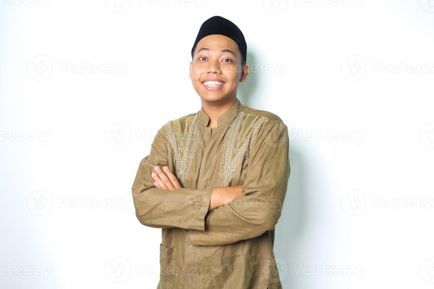 Aziatisch moslim Mens glimlachen met gevouwen armen en op zoek Bij camera vervelend koko kleren Aan eid al fitr viering geïsoleerd Aan wit achtergrond foto