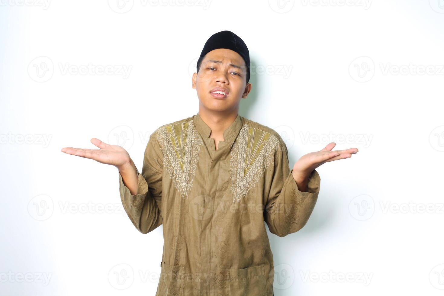 benadrukt Aziatisch moslim Mens verhogen palm twee kant naar presenteren met verward uitdrukking geïsoleerd in wit achtergrond foto