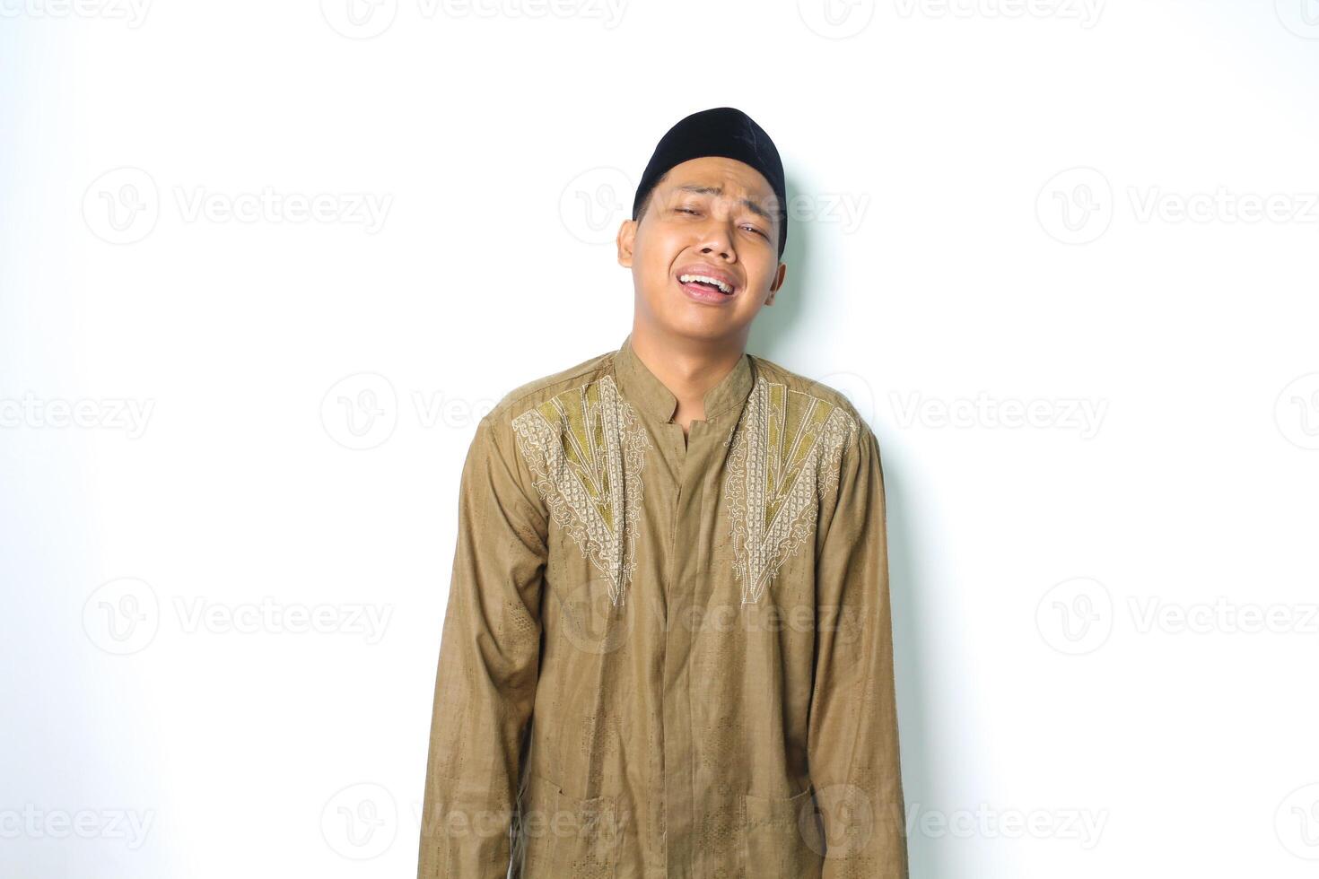 verdrietig Aziatisch moslim Mens huilen in eid al fitr viering vervelend koko kleren geïsoleerd Aan wit achtergrond foto