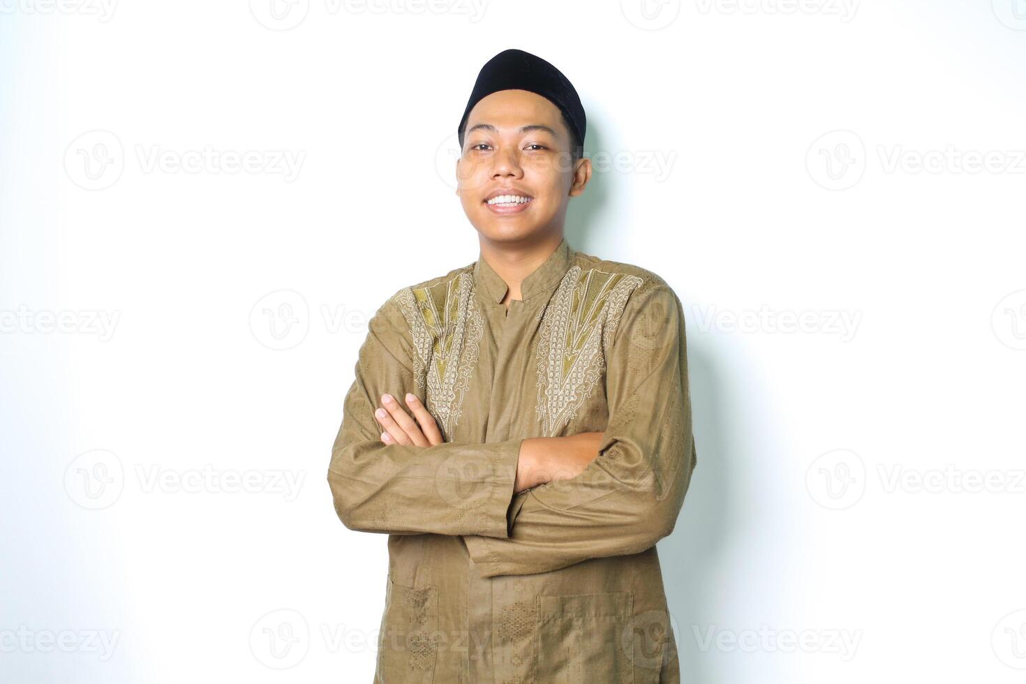 glimlachen Aziatisch Moslim Mens staand Aan geïsoleerd wit achtergrond met gevouwen armen en glimlachen vertrouwen vervelend koko kleren Islamitisch jurk foto