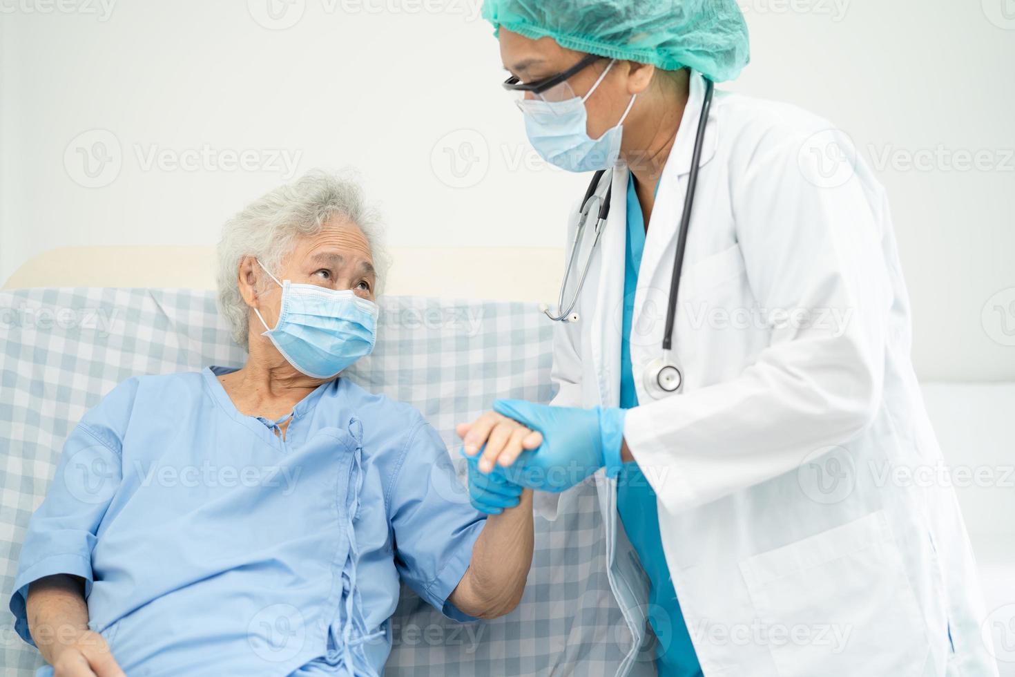 arts helpt aziatische senior of oudere oude dame vrouw patiënt die een gezichtsmasker draagt in het ziekenhuis om de veiligheidsinfectie te beschermen en covid-19 coronavirus te doden. foto