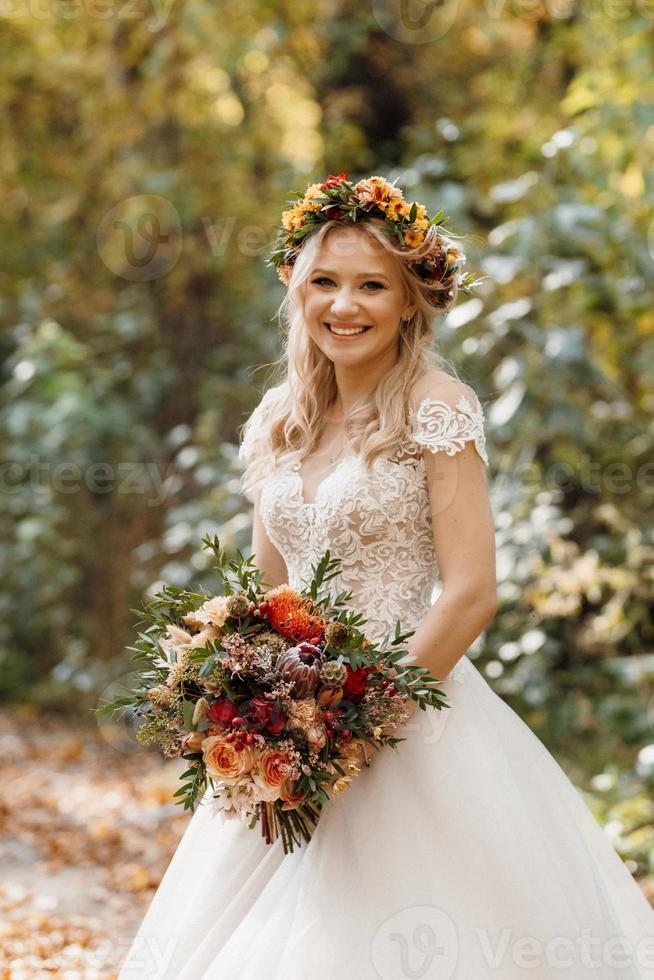 blond meisje in een trouwjurk in het herfstbos foto