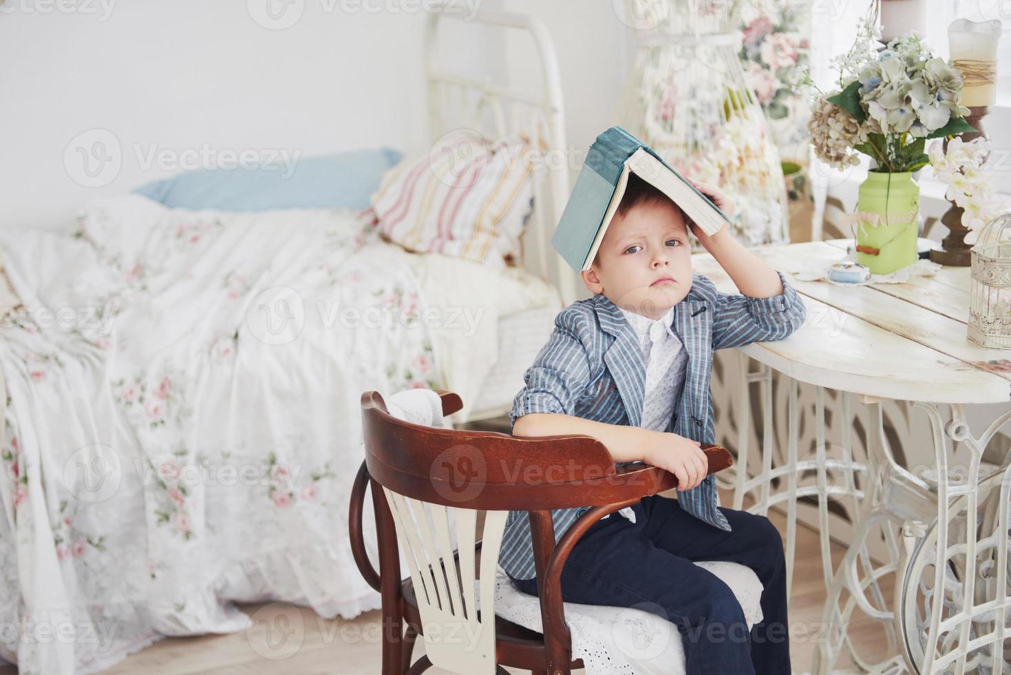 foto van ijverige schooljongen met boek op zijn hoofd wil niet studeren en naar school gaan