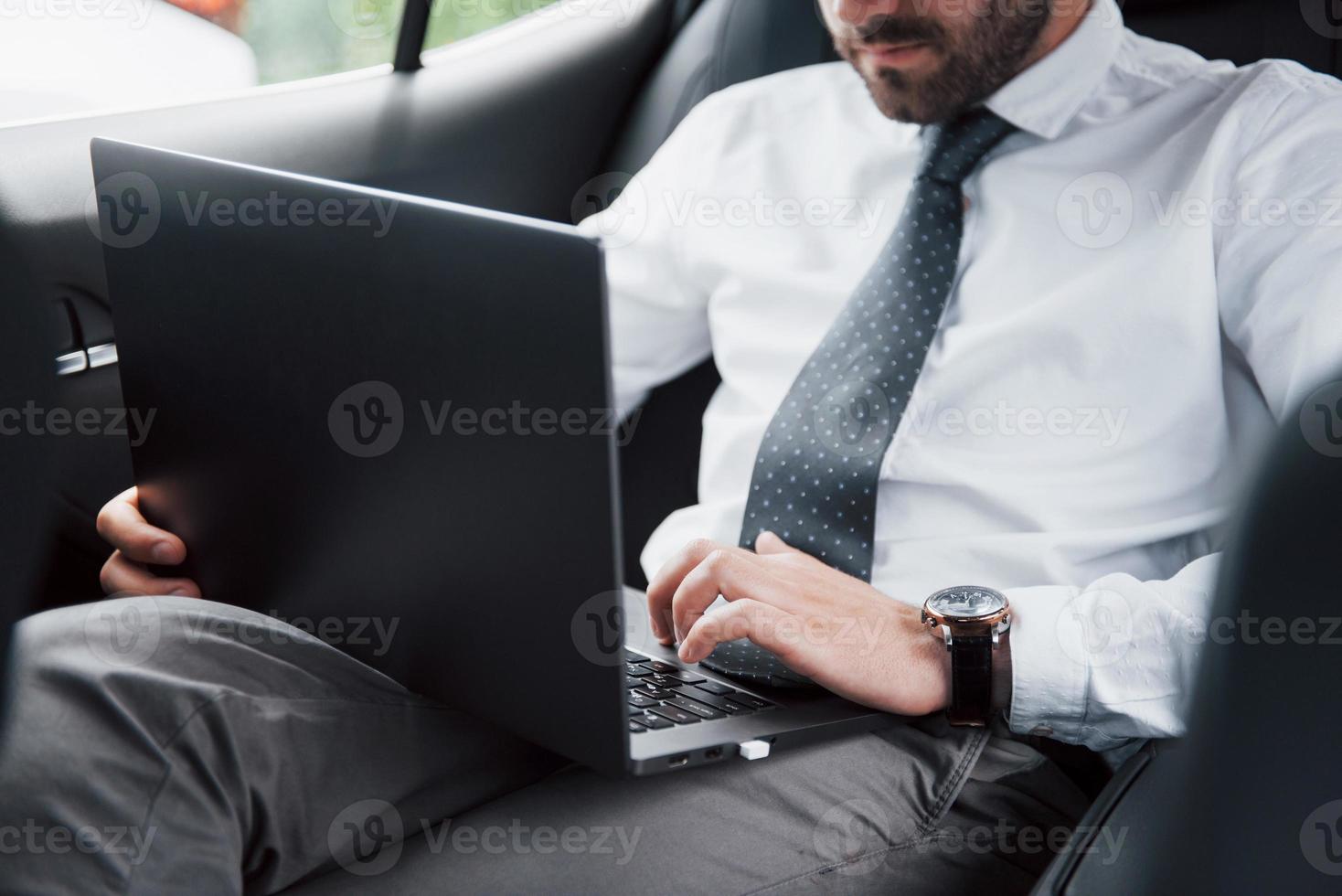 zakenman die laptop gebruikt om in de auto te werken foto