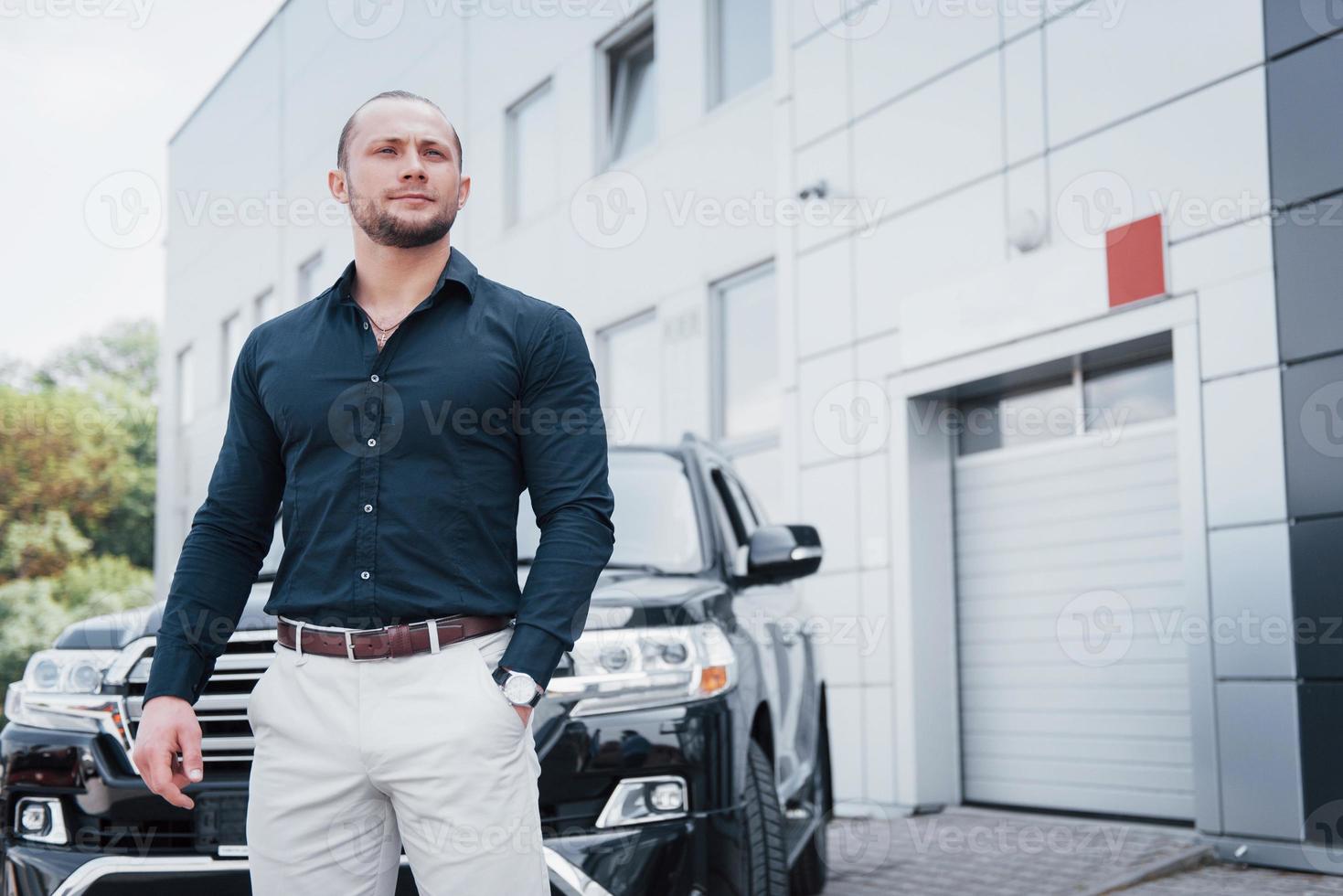 een jonge, solide zakenman en zijn auto in de buurt van het kantoor foto