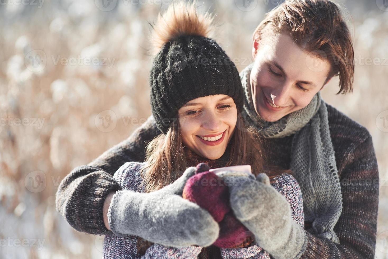 foto van gelukkige man en mooie vrouw met kopjes buiten in de winter. wintervakantie en vakantie. kerst paar gelukkige man en vrouw drinken warme wijn. verliefd stel