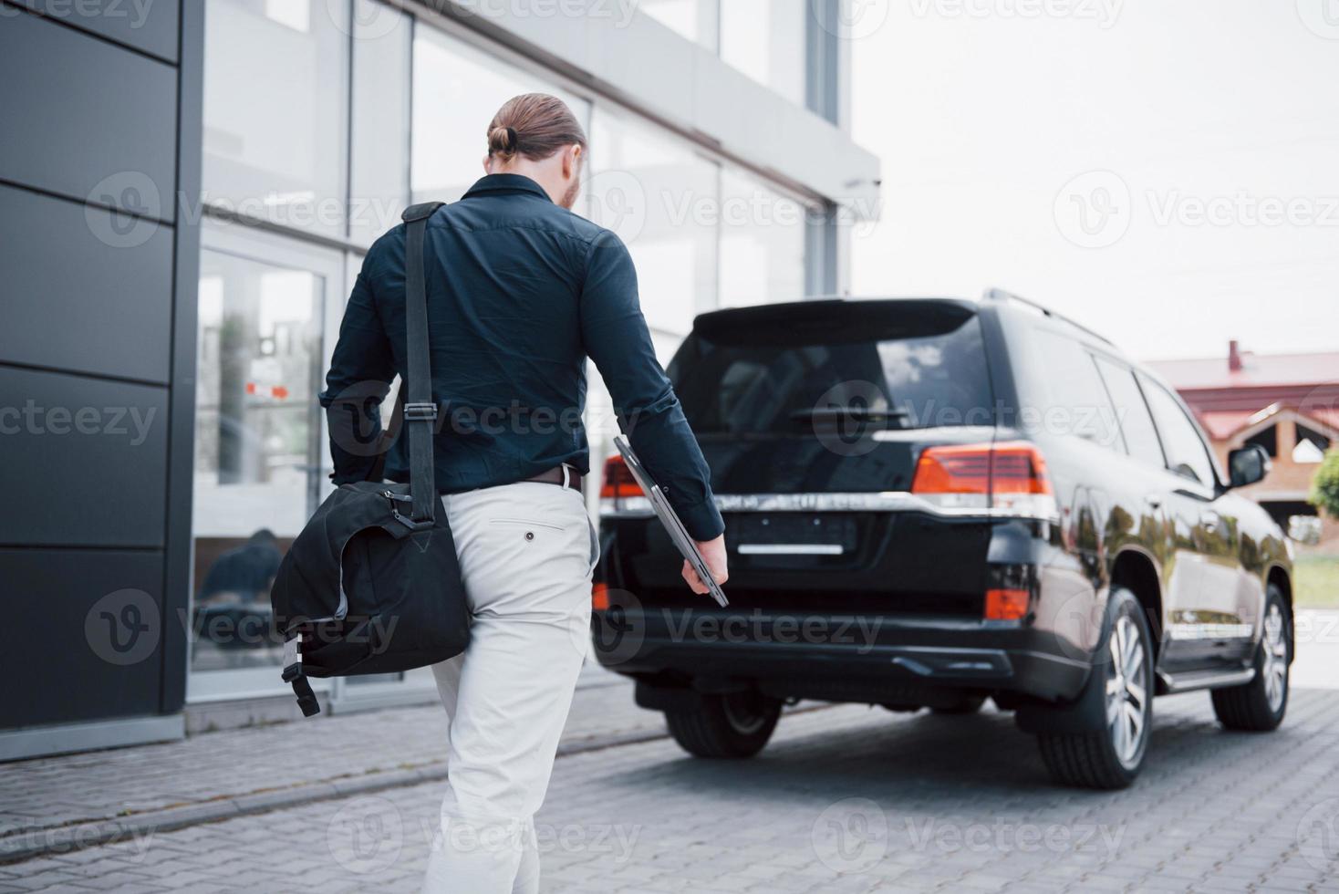 een jonge, solide zakenman en zijn auto in de buurt van het kantoor foto