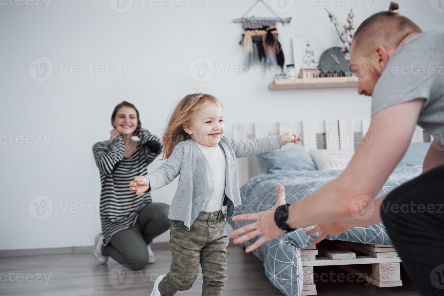 gelukkige familie heeft thuis plezier. moeder, vader en dochtertje met knuffel genieten van het samenzijn foto