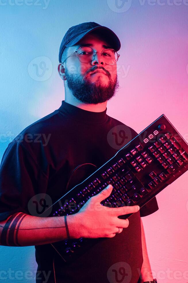 jong Latijns Amerikaans Mens met baard en bril Holding een gaming toetsenbord. foto