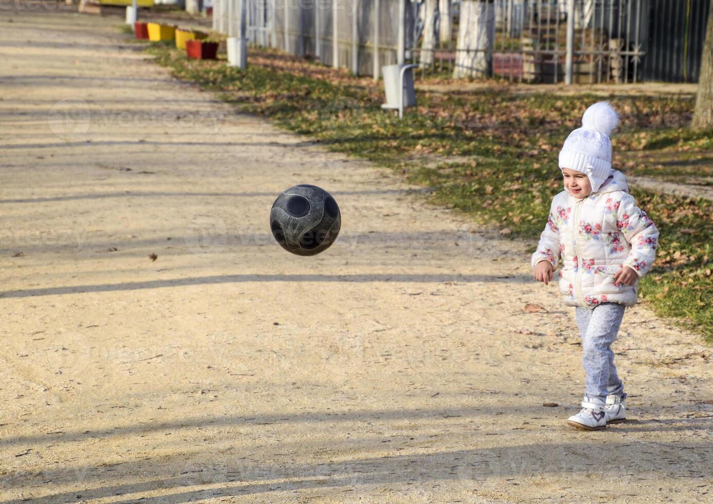 de kind is spelen met de bal. een weinig vier jaar oud meisje Toneelstukken met een Amerikaans voetbal. foto