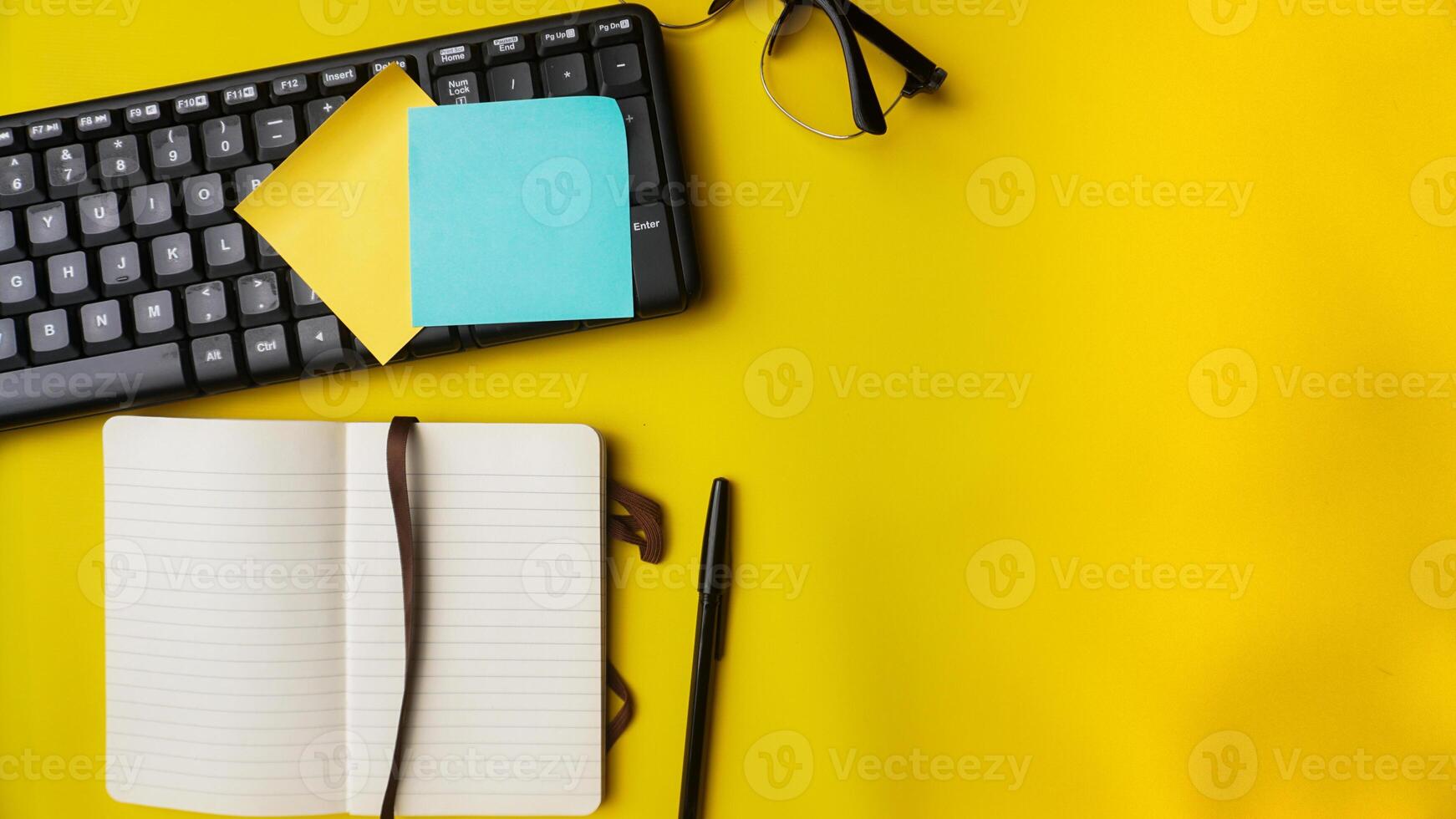 werkruimte bureau met notitieboekjes, pennen, toetsenbord, bril, planten, en koffie Aan blauw achtergrond foto
