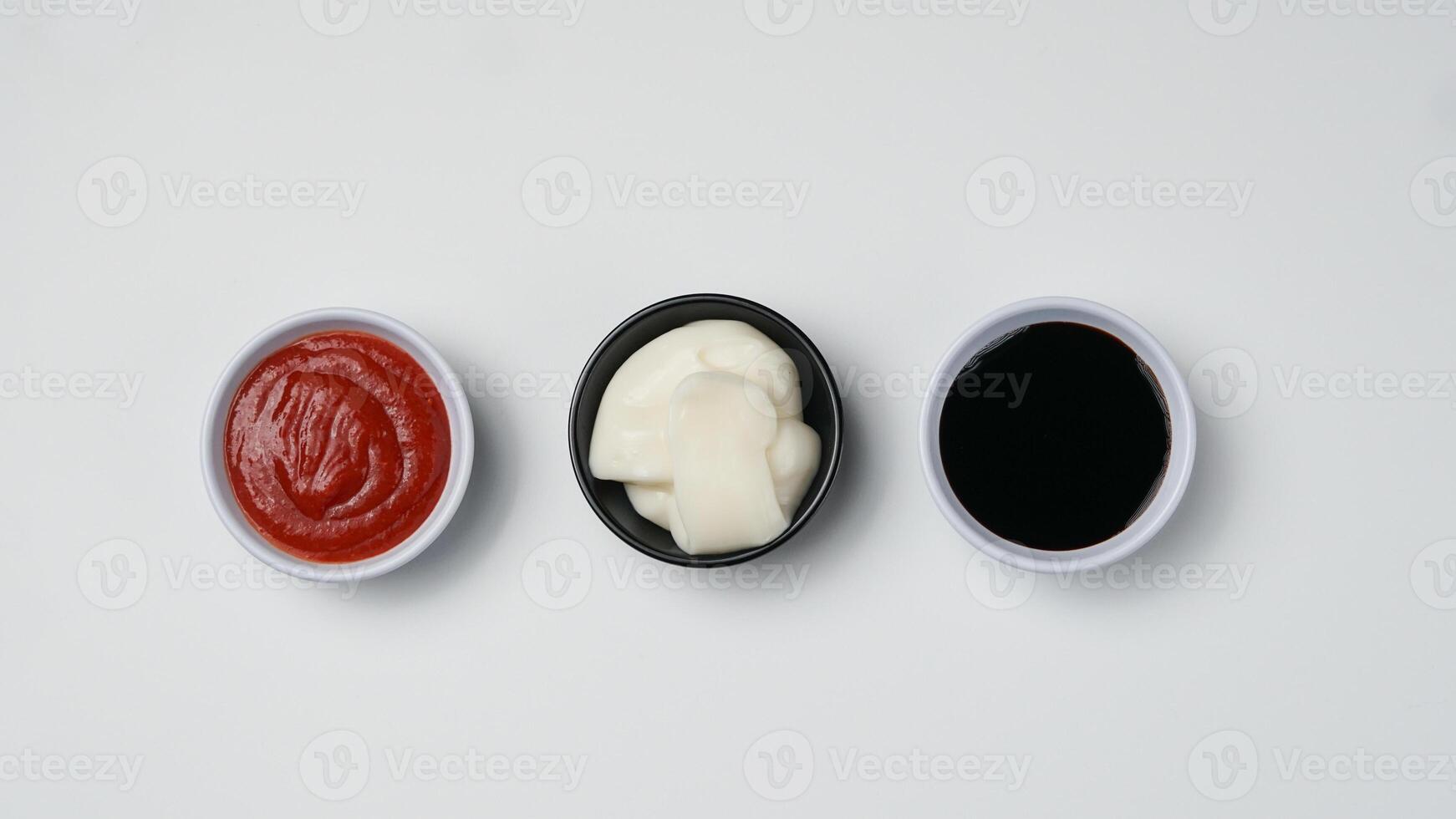 drie sauzen ketchup mayonaise, zoet soja saus en Chili saus in zwart kom geïsoleerd Aan wit achtergrond foto