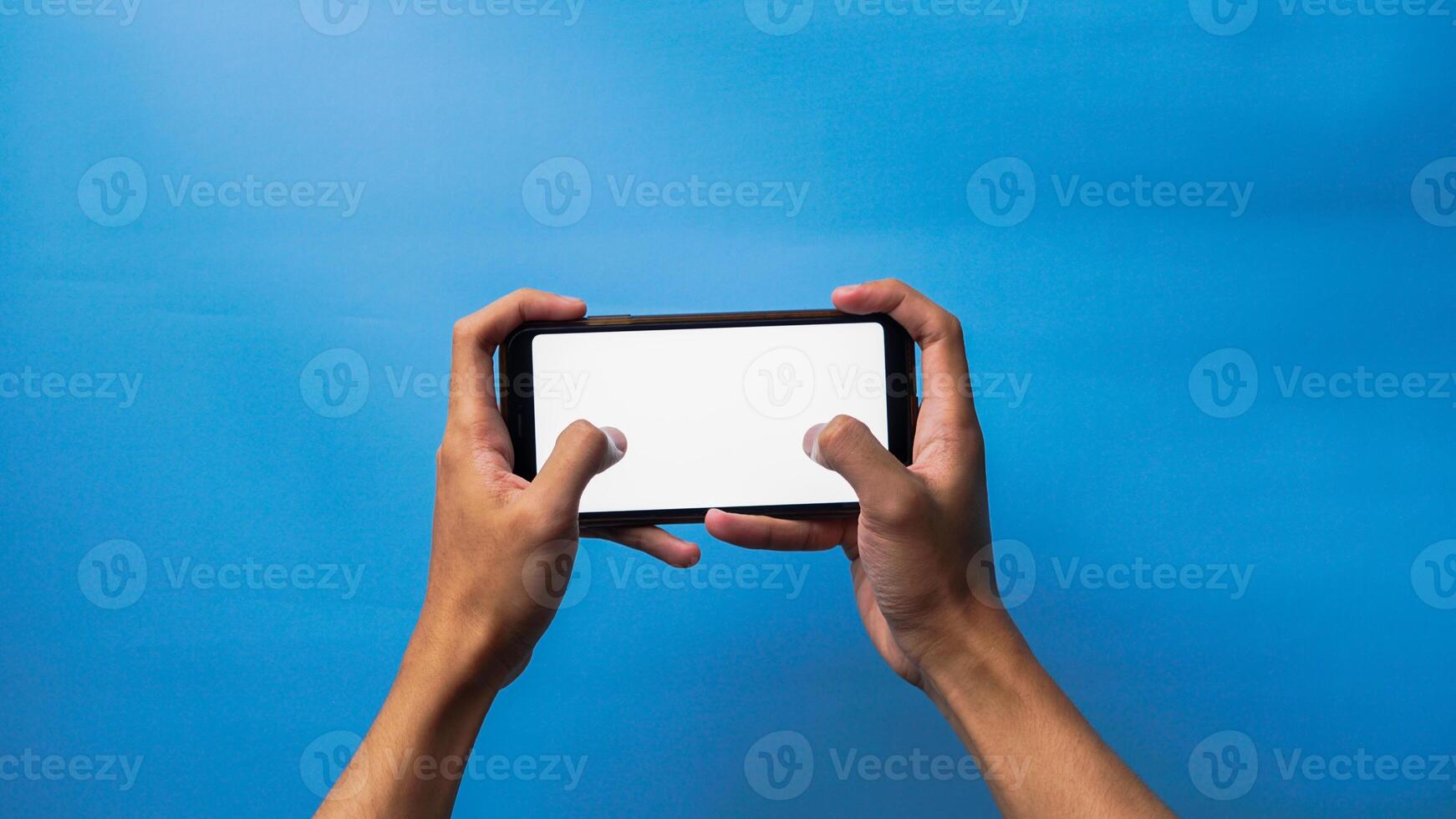 hand- van Mens Holding mobiel smartphone met gebaar spelen spel Aan blauw achtergrond foto