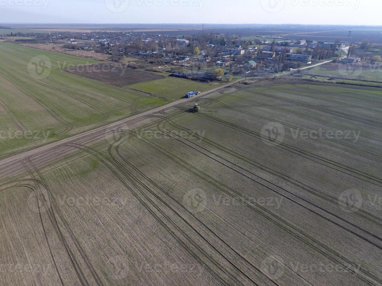 trekker met scharnierend systeem van sproeien pesticiden. bemesting met een tractor, in de het formulier van een aërosol, Aan de veld- van winter tarwe. foto