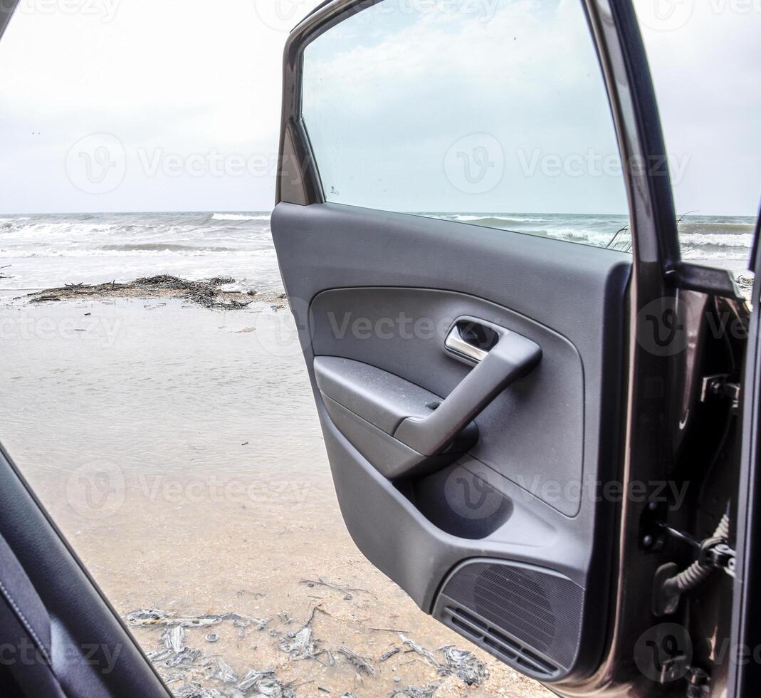 een Open auto deur tegen de zee. storm Aan de zee foto