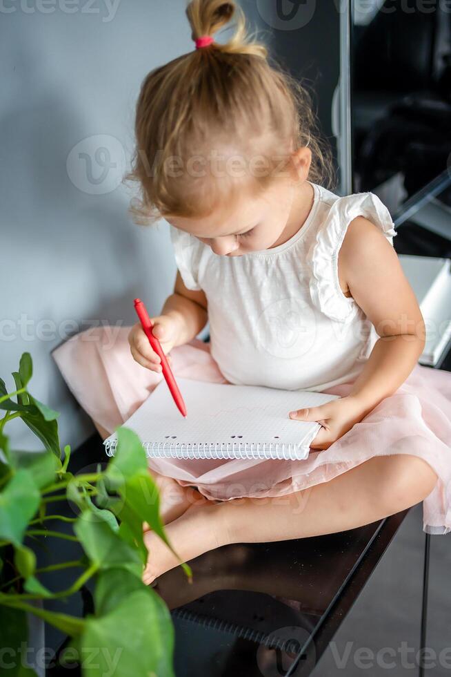 weinig meisje trek of schrijven door rood potlood Bij huis. kind creativiteit en onderwijs concept foto