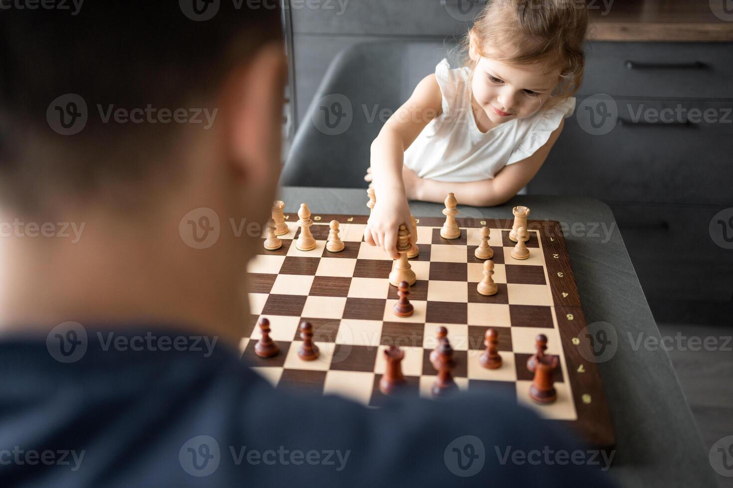 vader onderwijs zijn weinig dochter naar Speel schaak Bij de tafel in huis keuken. de concept vroeg kinderjaren ontwikkeling en onderwijs. familie vrije tijd, communicatie en recreatie. foto