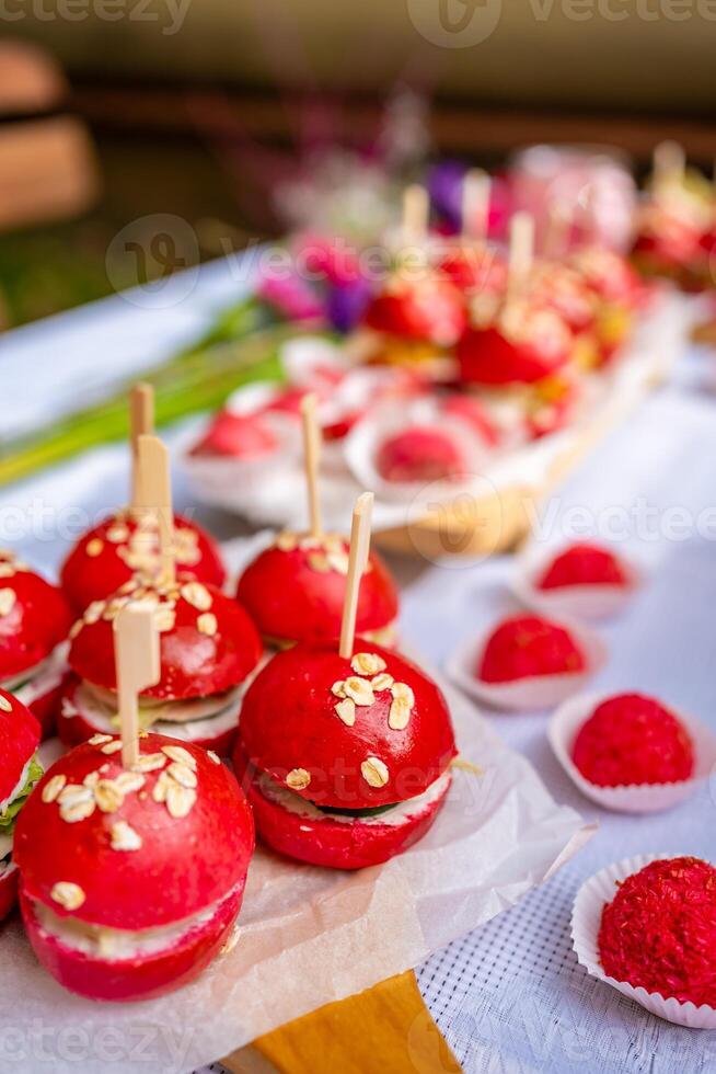 eigengemaakt krokant kip hamburgers. detailopname vers en sappig gekleurde roze hamburger met kip, kaas, sla, gepekeld komkommer, saus en gekleurde rode biet bun Aan de tafel. foto