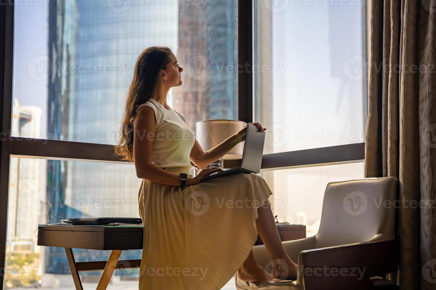 elegant zakenvrouw freelancer met laptop zittend Aan de tafel en genieten van panoramisch visie in de stad achtergrond. laag sleutel foto. hoog kwaliteit foto