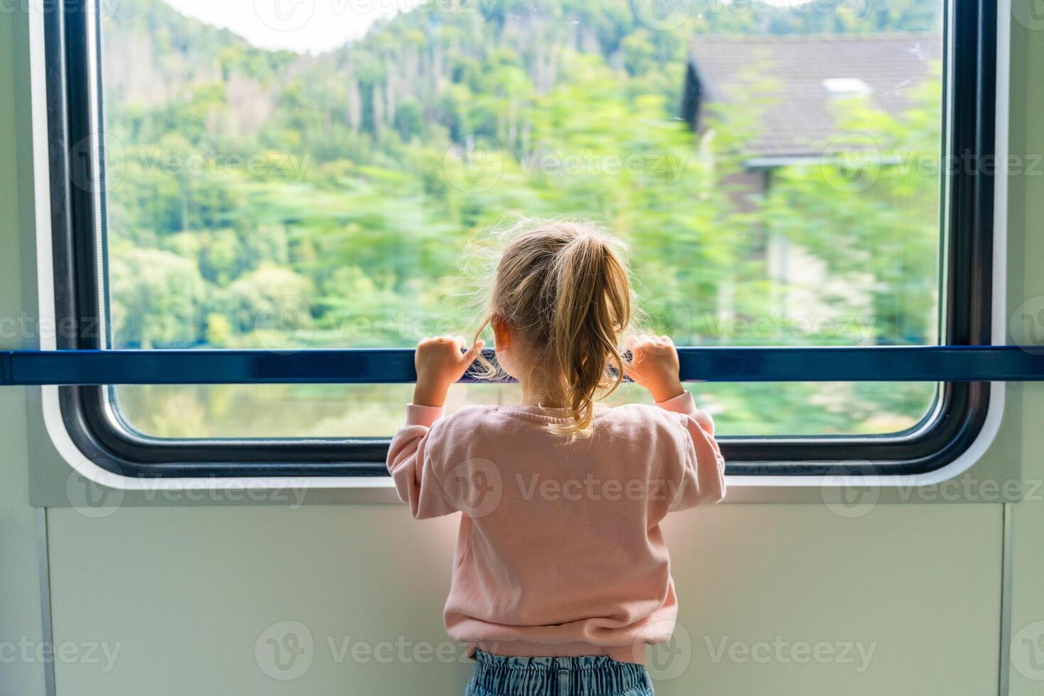 mooi weinig meisje op zoek uit trein venster buiten, gedurende in beweging. op reis door spoorweg in Europa foto