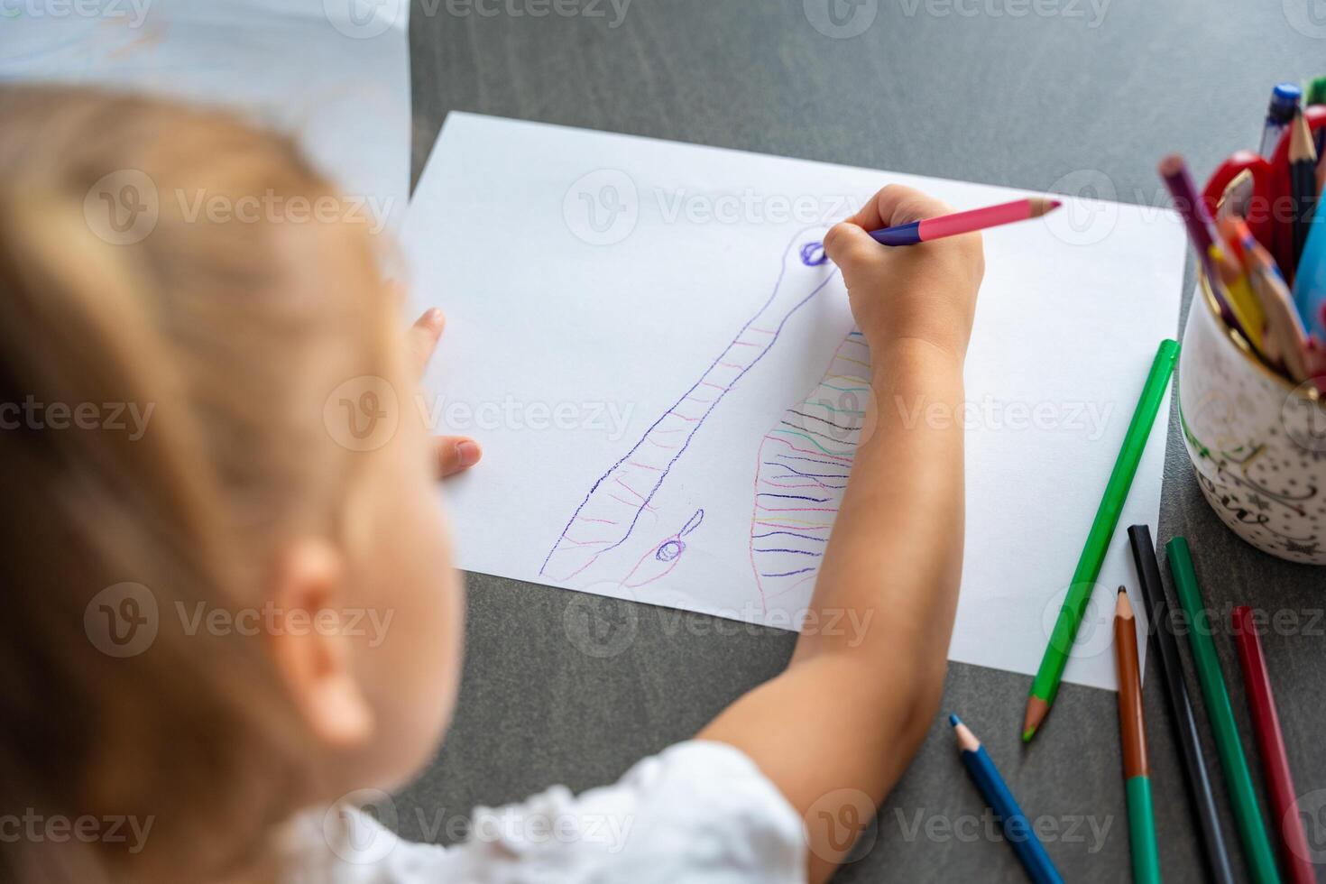 weinig meisje trekt met gekleurde potloden in huis. foto