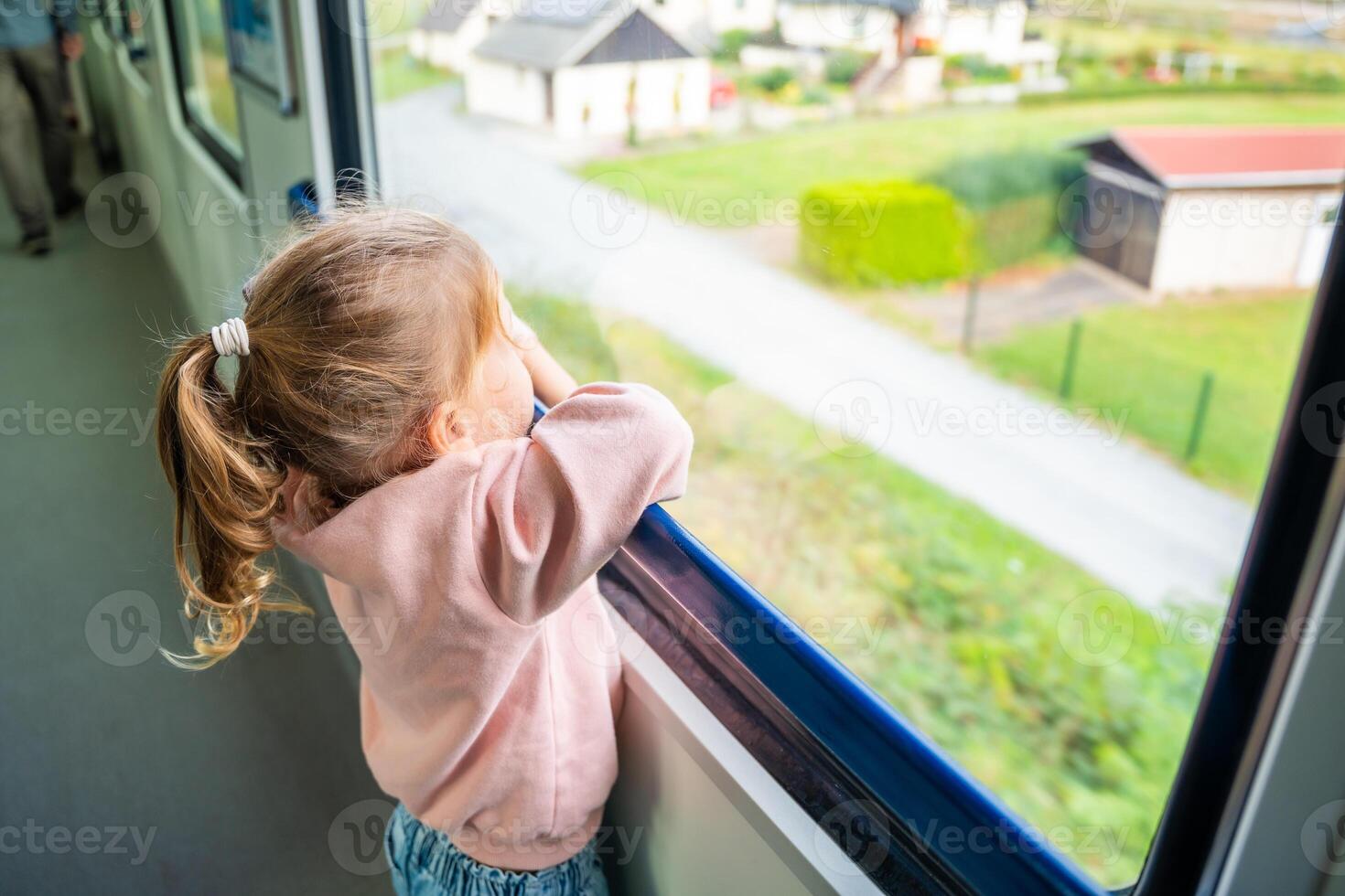 mooi weinig meisje op zoek uit trein venster buiten, gedurende reizend. op reis door spoorweg in Europa foto