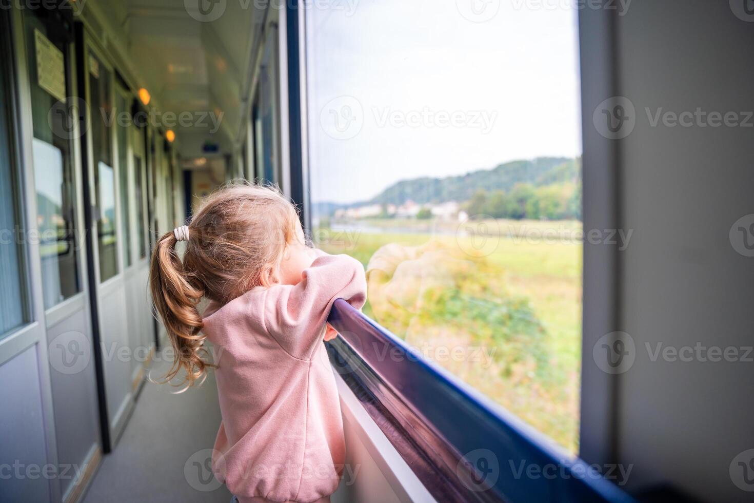 mooi weinig meisje op zoek uit trein venster buiten, gedurende reizend. op reis door spoorweg, Europa foto