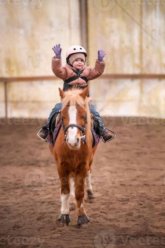 weinig kind rijden les. drie jaar oud meisje ritten een pony en doet opdrachten. hoog kwaliteit foto
