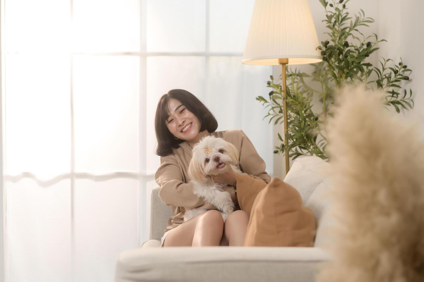 gelukkig jong Aziatisch vrouw knuffelen en uitgeven tijd met schattig hond in leven kamer. foto