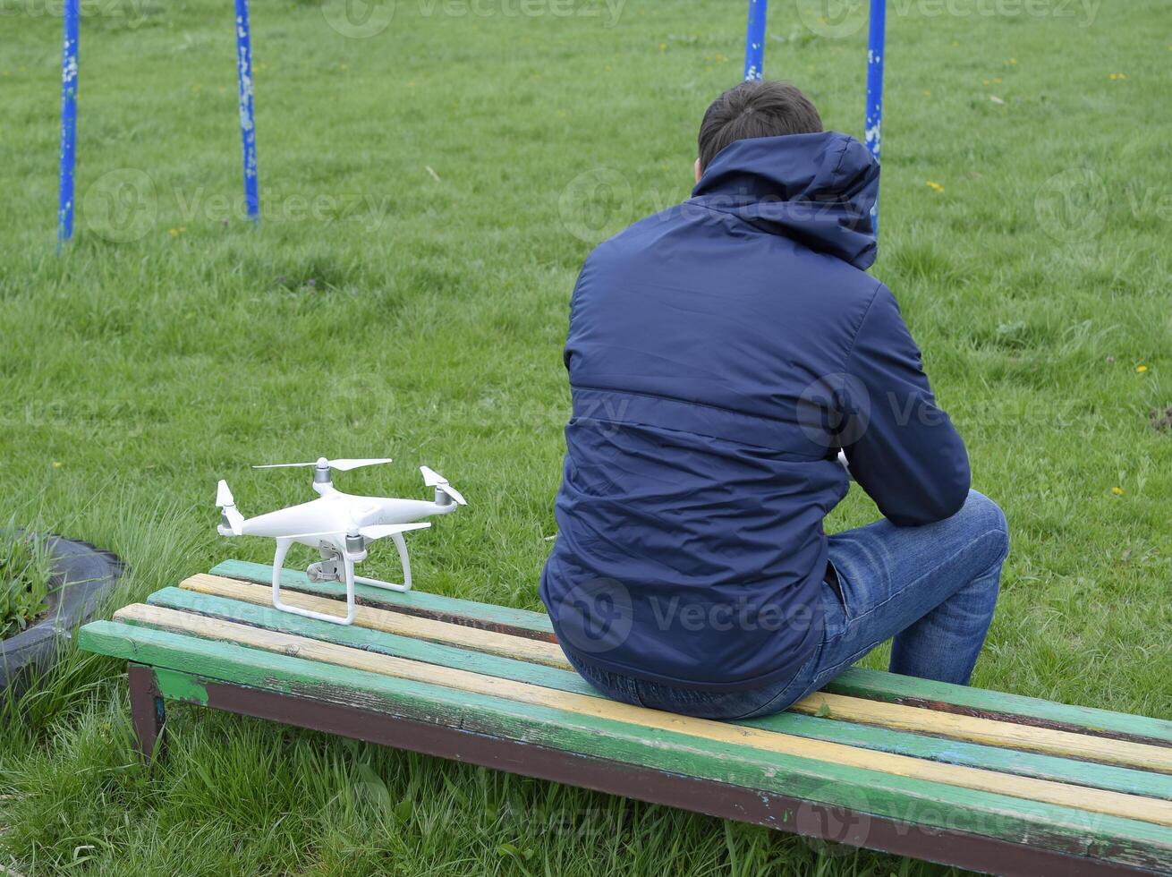 een Mens met een afgelegen controle quadroopter in zijn handen is zittend foto