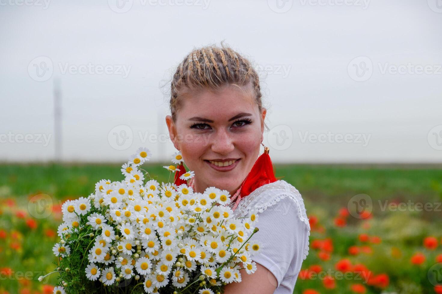 jong meisje met een boeket van madeliefjes in veld. madeliefjes Aan een papaver veld. foto