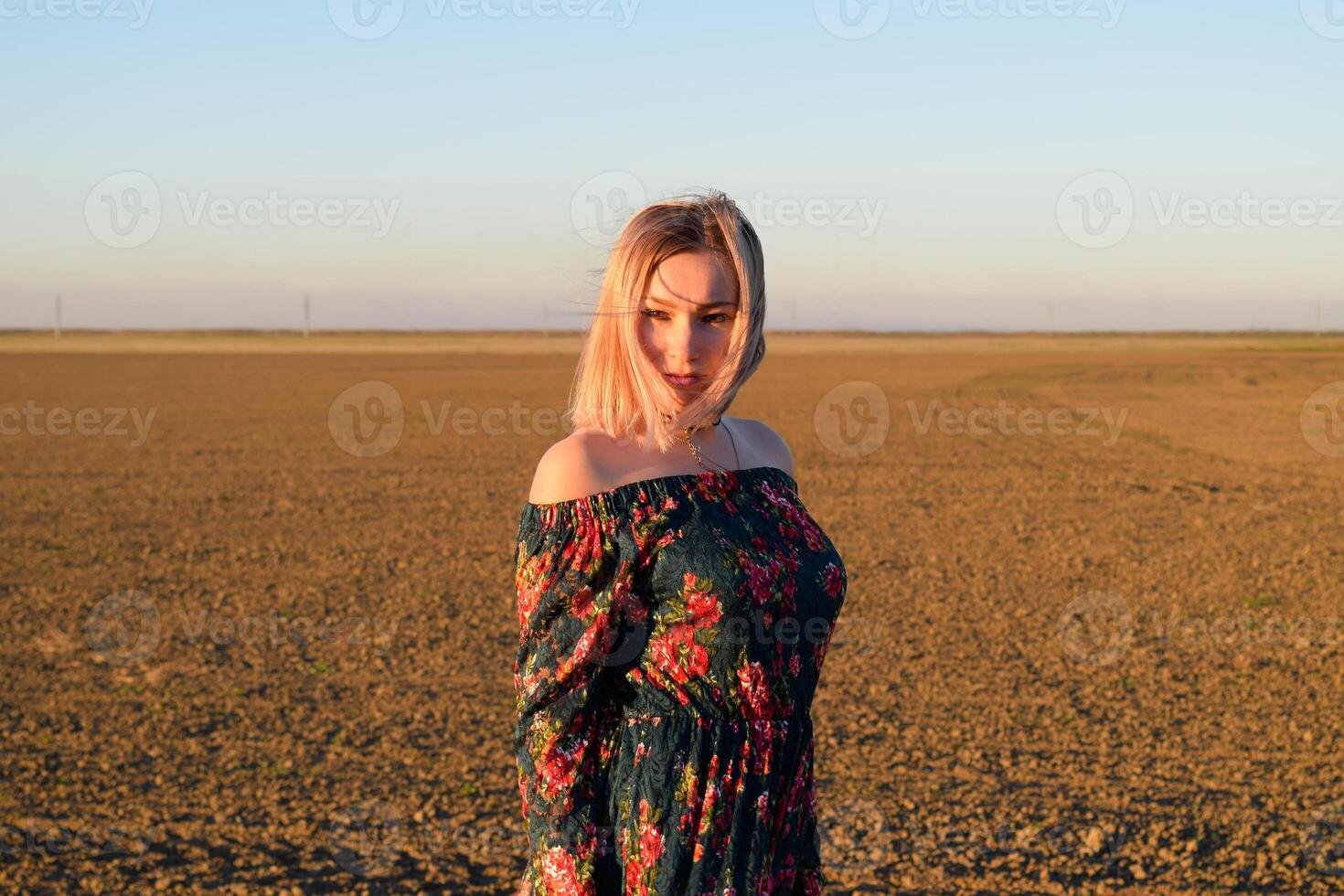 vrouw in een geploegd veld- in een rood Zwart jurk Aan een zonsondergang achtergrond. foto