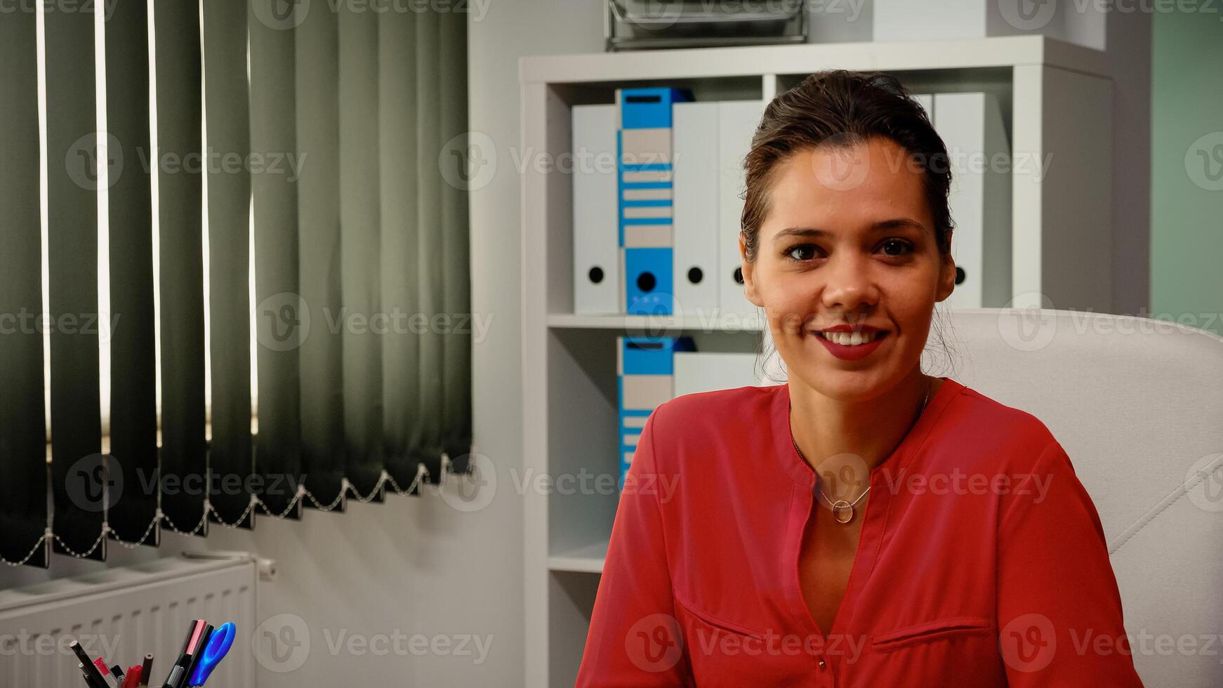 portret van dame glimlachen in voorkant van camera in modern kantoor kamer. langzaam beweging van spaans freelancer werken in professioneel werkplaats in persoonlijk zakelijke bedrijf op zoek Bij webcam foto