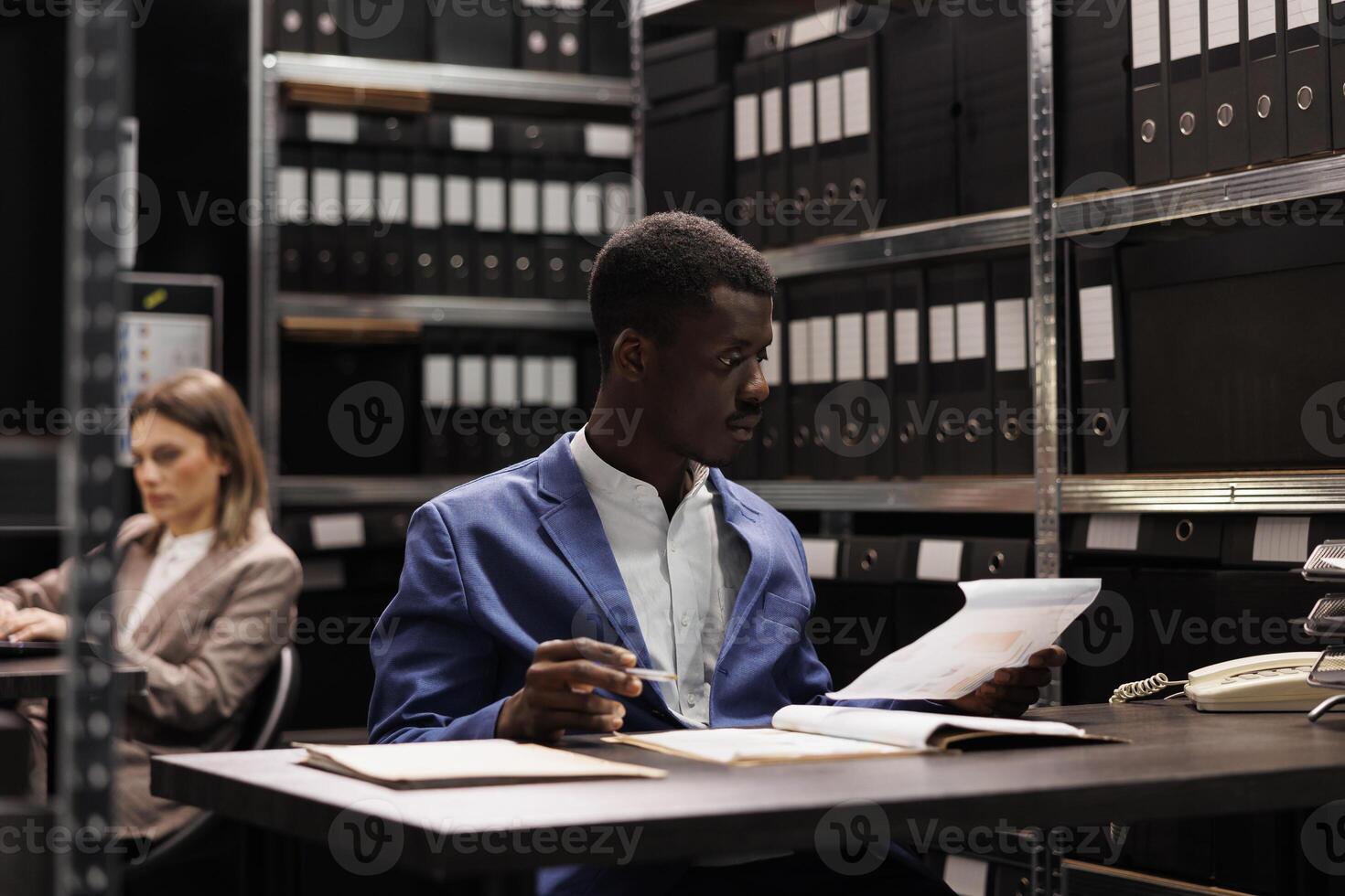 Afrikaanse Amerikaans boekhouder analyseren beheer bestanden, zoeken voor administratief verslag doen van in zakelijke opslagplaats. zakenman werken laat Bij nacht Bij boekhouding Vermelding in opslagruimte kamer foto