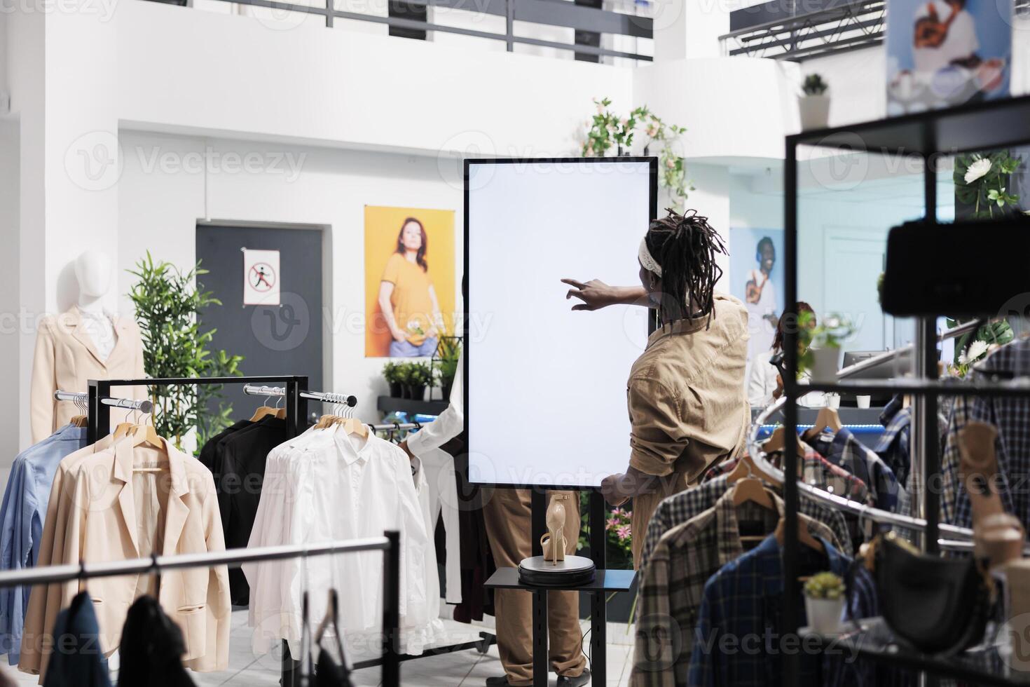 Afrikaanse Amerikaans Mens terwijl gebruik makend van slim interactief Scherm bord in kleding op te slaan. klant tikken Aan blanco wit scherm bespotten omhoog voor schoenen digitaal advertenties en informatie in boodschappen doen winkelcentrum winkel foto