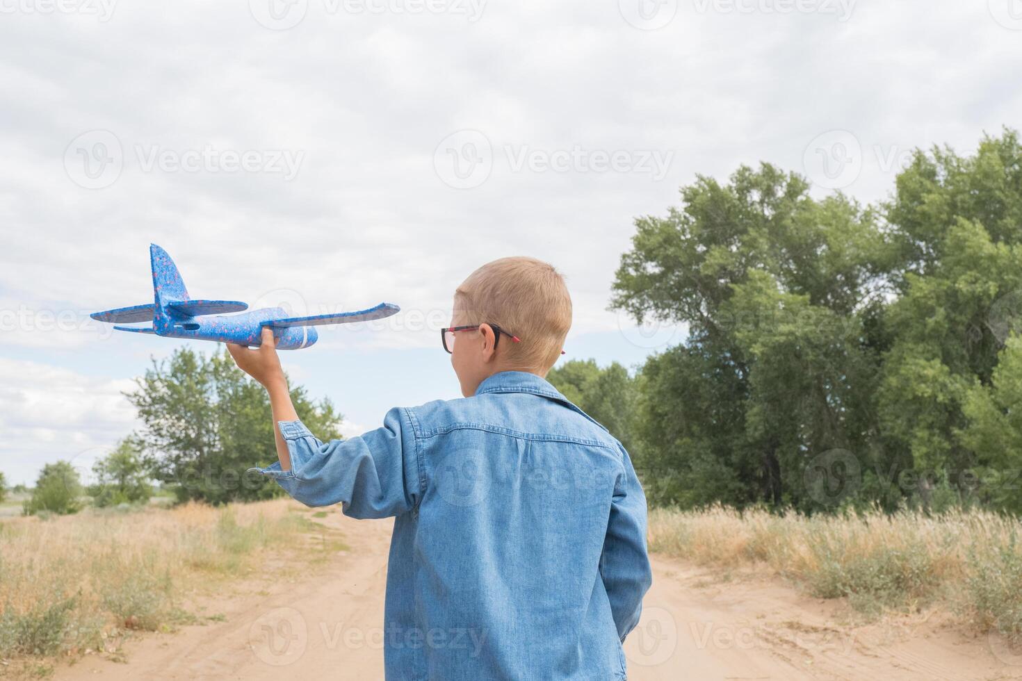 achterzijde visie van een kind jongen met een vliegtuig dromen van op reis in de zomer in natuur Aan een zonnig dag foto