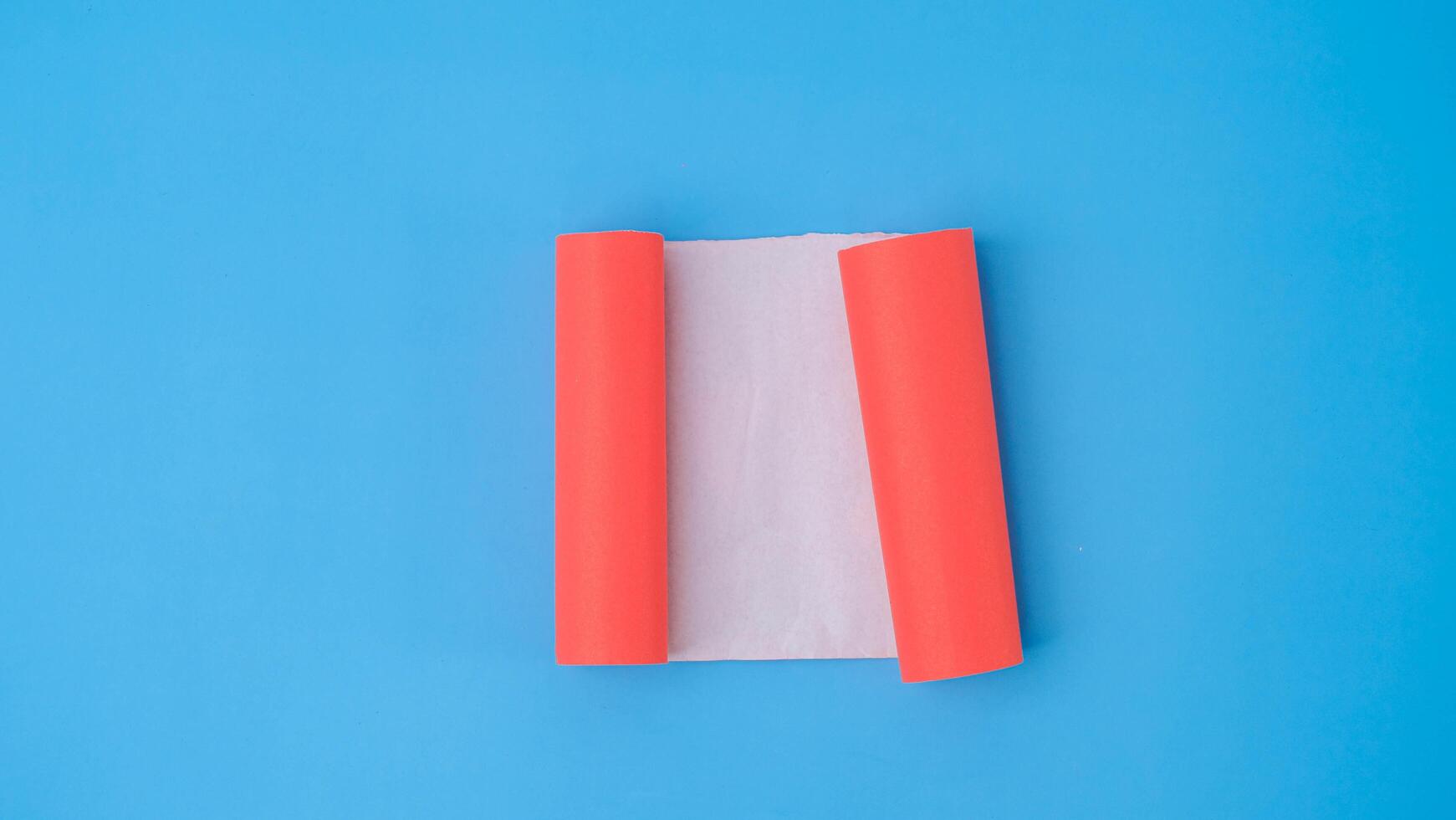 een oranje gerold plein papier is verspreiding uit in een blanco wit vel Aan een licht blauw achtergrond. verfrommeld blanco wit papier met kopiëren ruimte voor tekst of reclame ruimte. foto