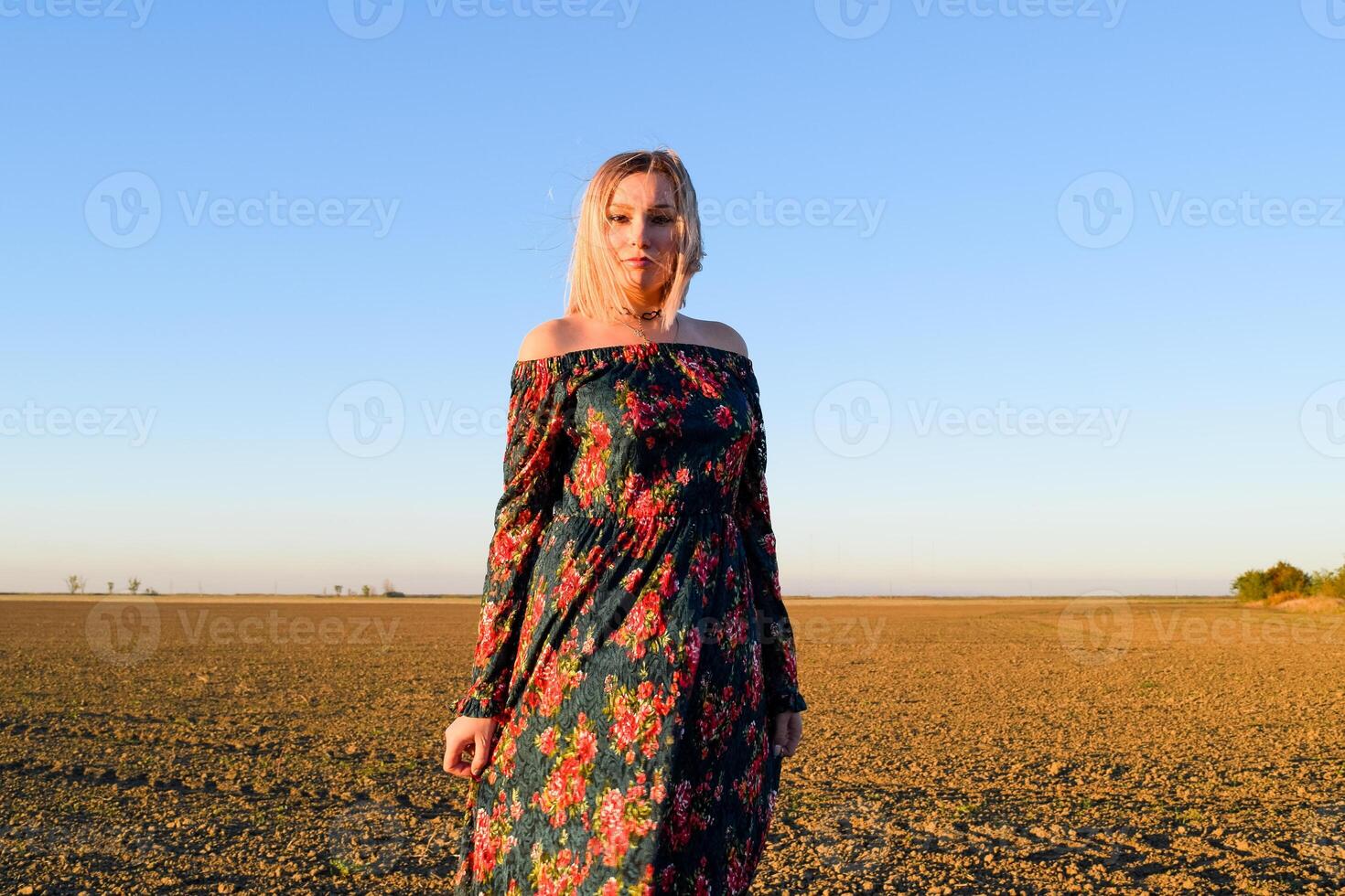 vrouw in een geploegd veld- in een rood Zwart jurk Aan een zonsondergang achtergrond. foto