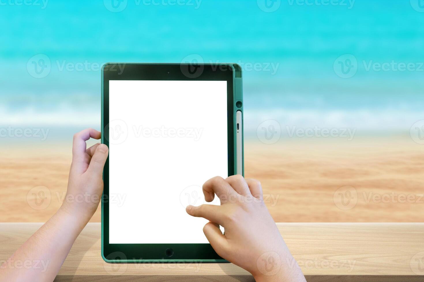 jongens hand- Holding een tablet Aan een houten tafel wazig strand achtergrond foto