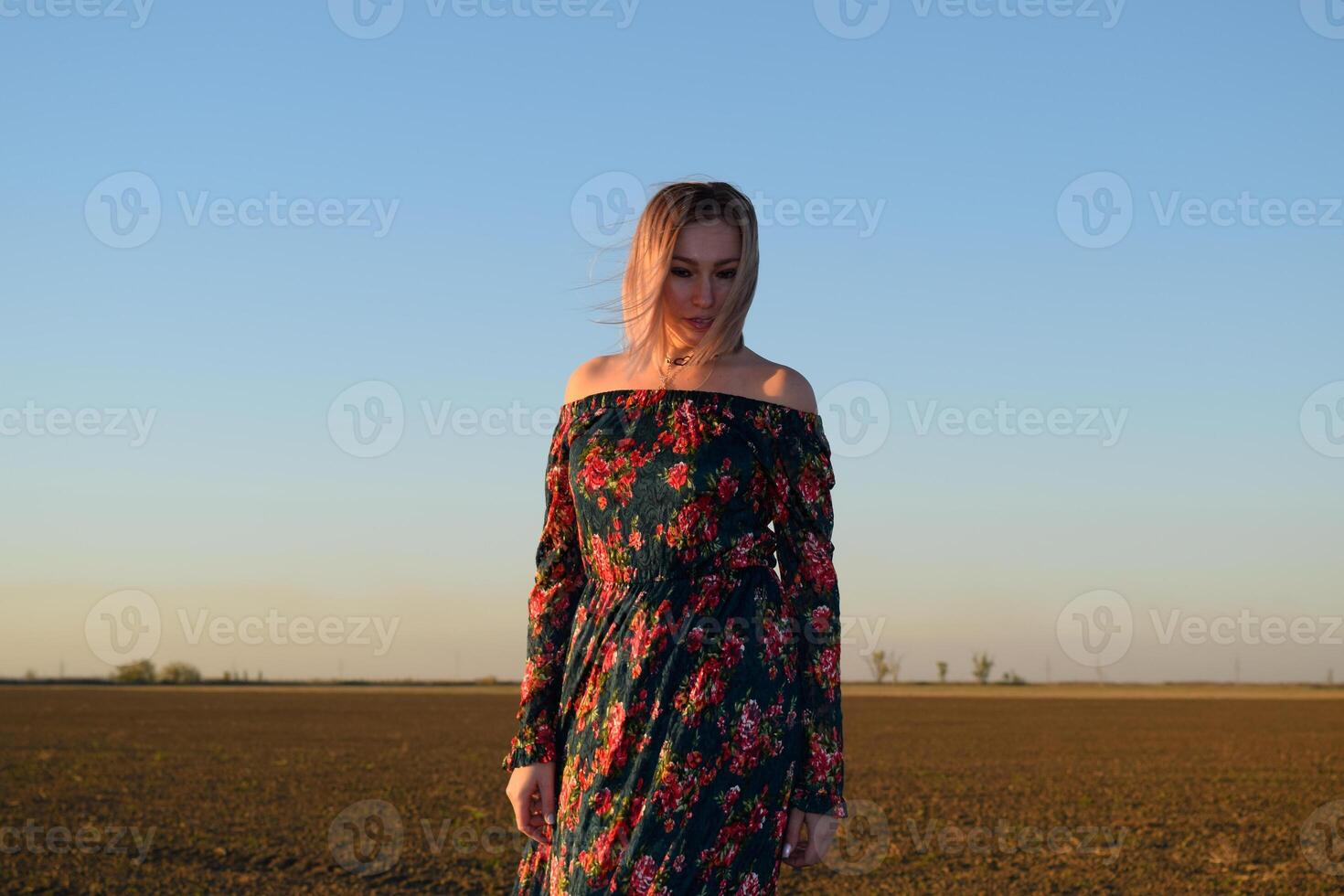 vrouw in een geploegd veld- in een rood Zwart jurk Aan een zonsondergang achtergrond. foto