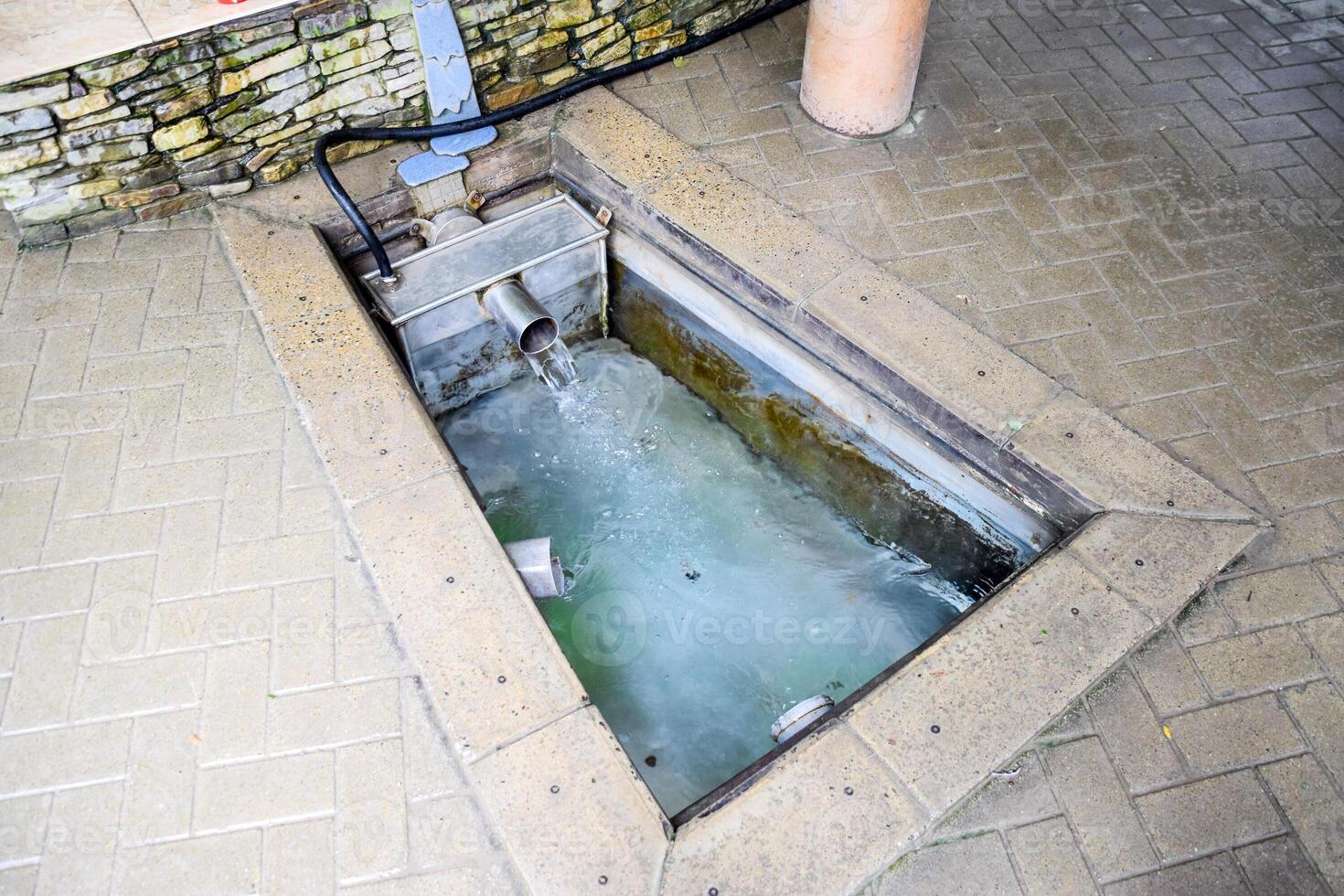 een klein zwemmen zwembad met heilig water van de de lente. een niche in de verdieping voor rekruteren water van een bron foto