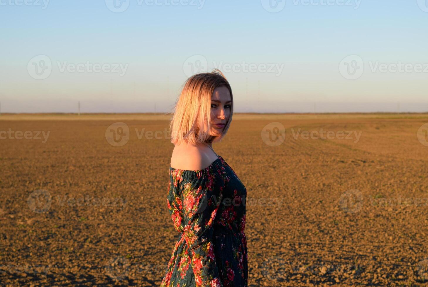 vrouw in een geploegd veld- in een rood Zwart jurk Aan een zonsondergang achtergrond. foto