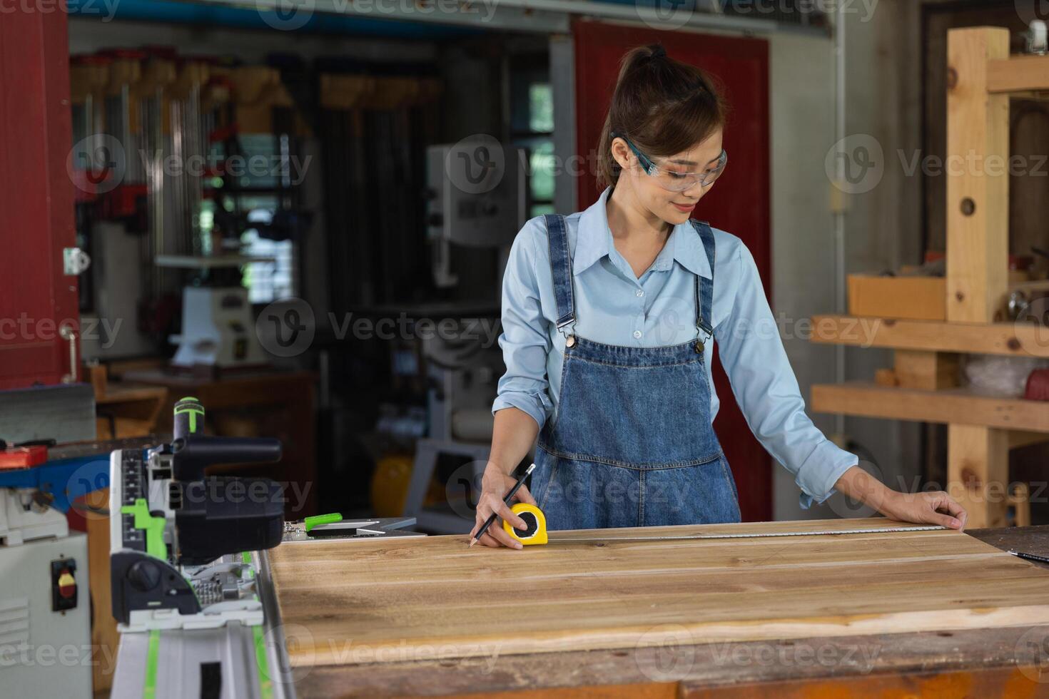 jong vrouw is opleiding naar worden een timmerman in werkplaats. timmerman werken met uitrusting Aan houten tafel. vrouw werken in een timmerwerk winkel. foto