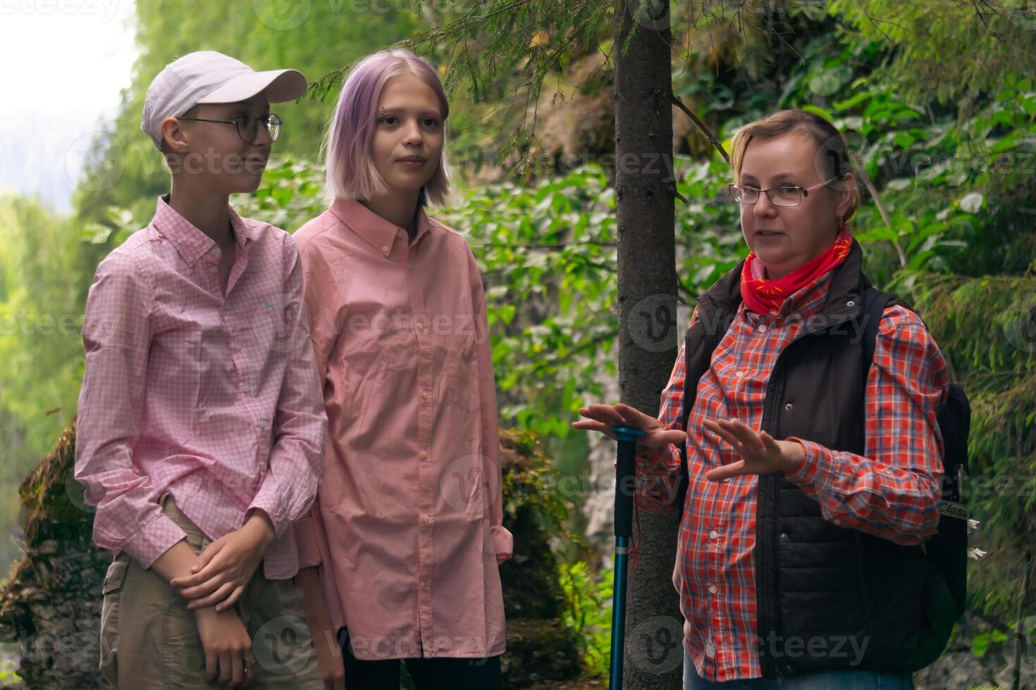 vrouw backpacker communiceert met twee tiener- meisjes tussen de rotsen in een natuurlijk landschap foto